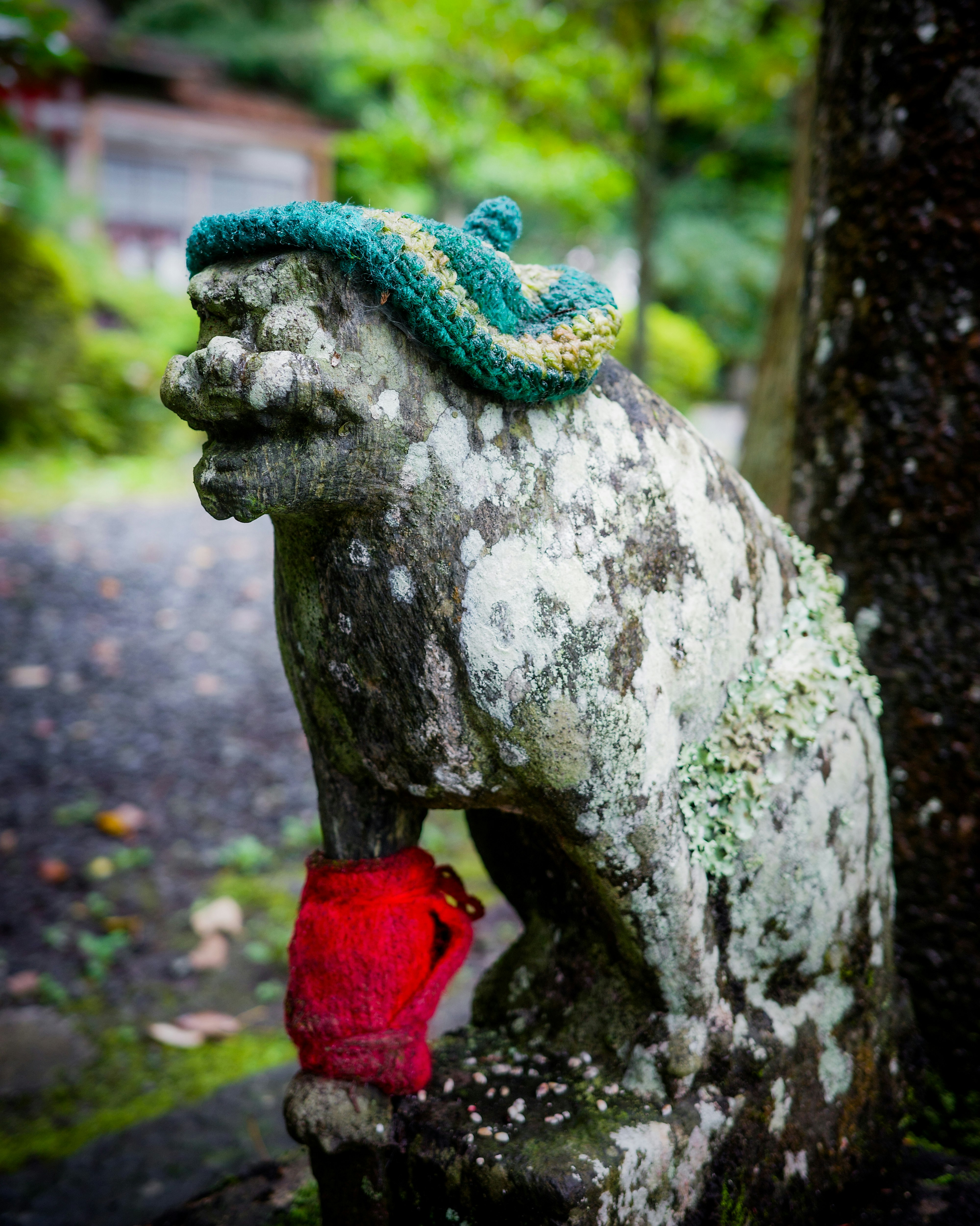 苔むした石の獅子像に青いよだれかけ
