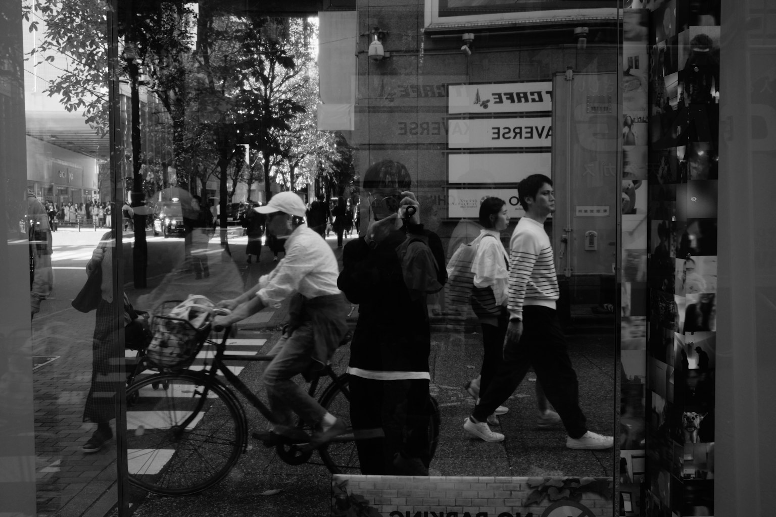 自転車に乗った人と歩行者が映る街の風景の反射