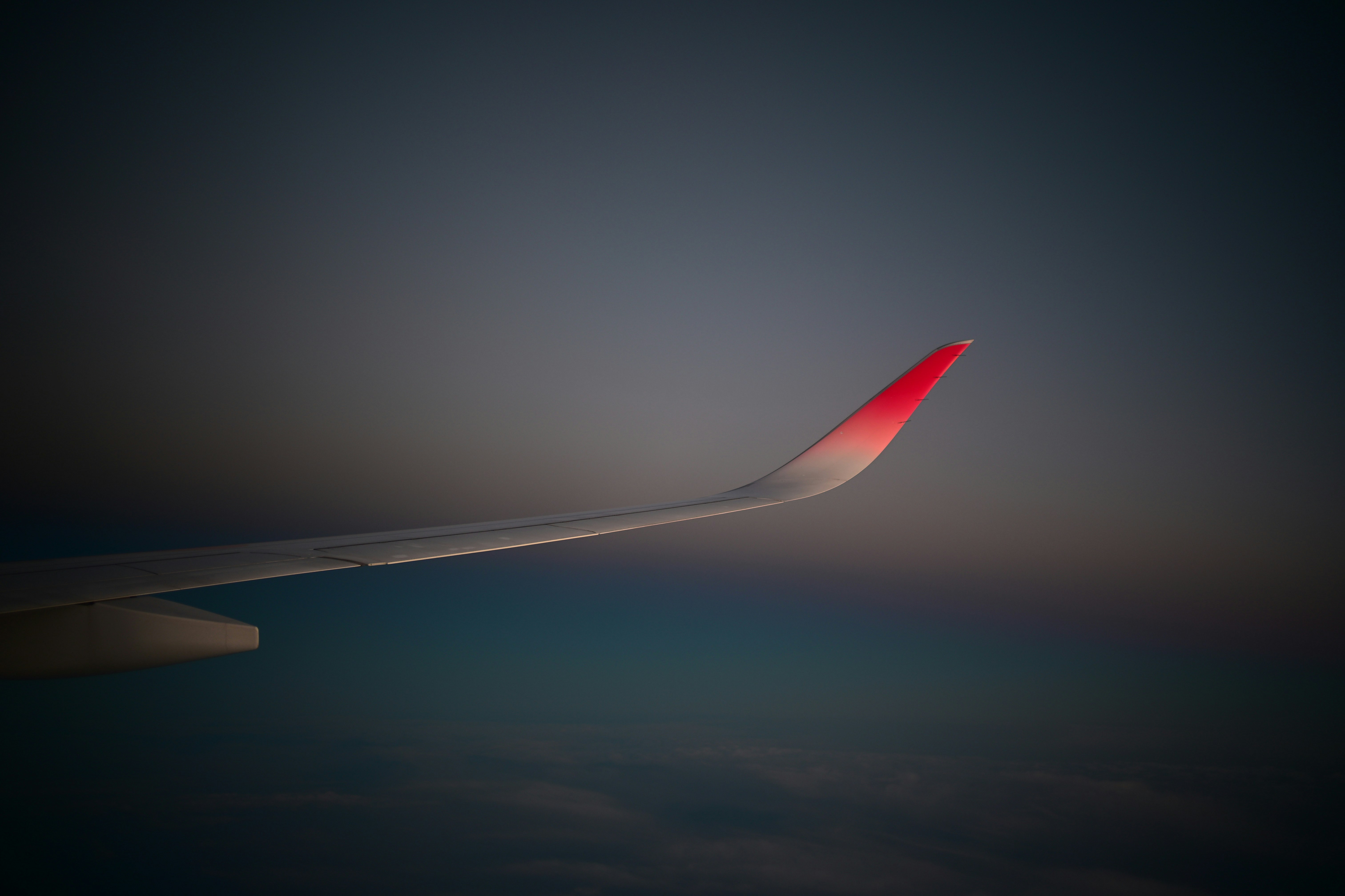 飛行機の翼の先端が夕暮れの空を背景に映える