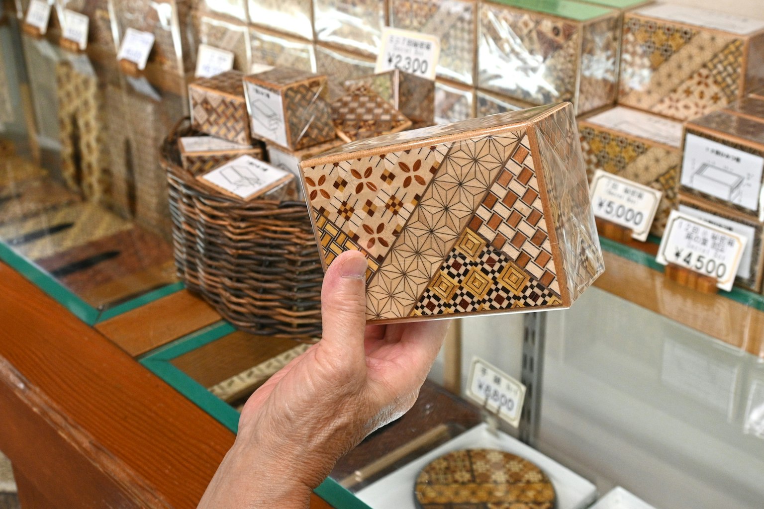 Scatola in legno decorativa tenuta in mano con vari oggetti in legno sullo sfondo