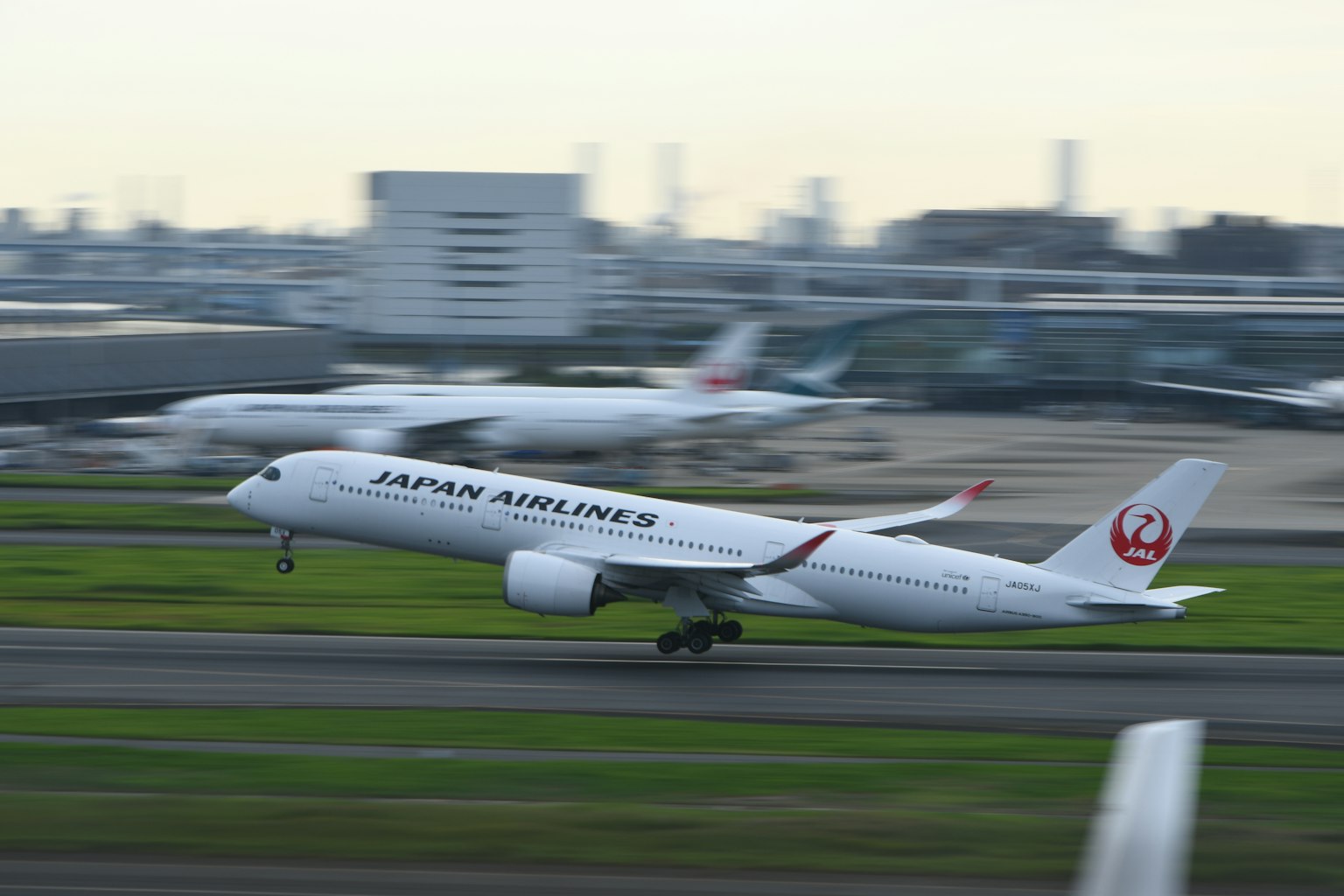 日本航空飞机在机场起飞，背景模糊