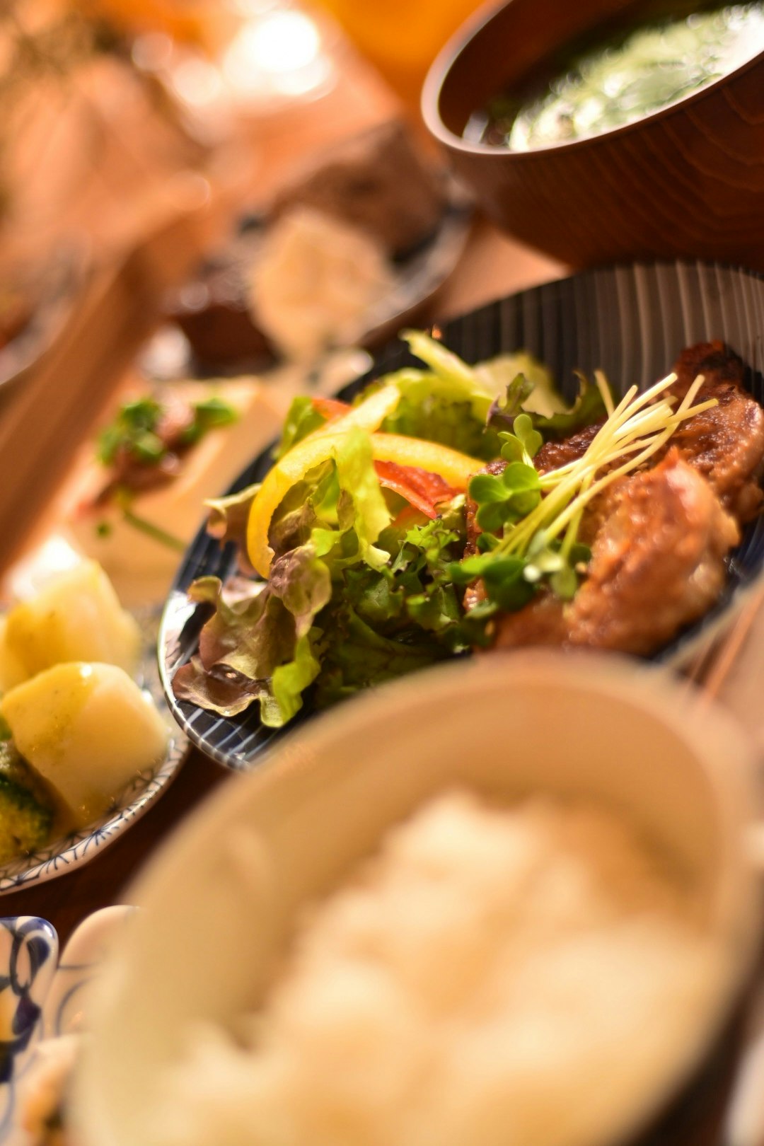 table avec salade et plats de viande dans des bols en bois