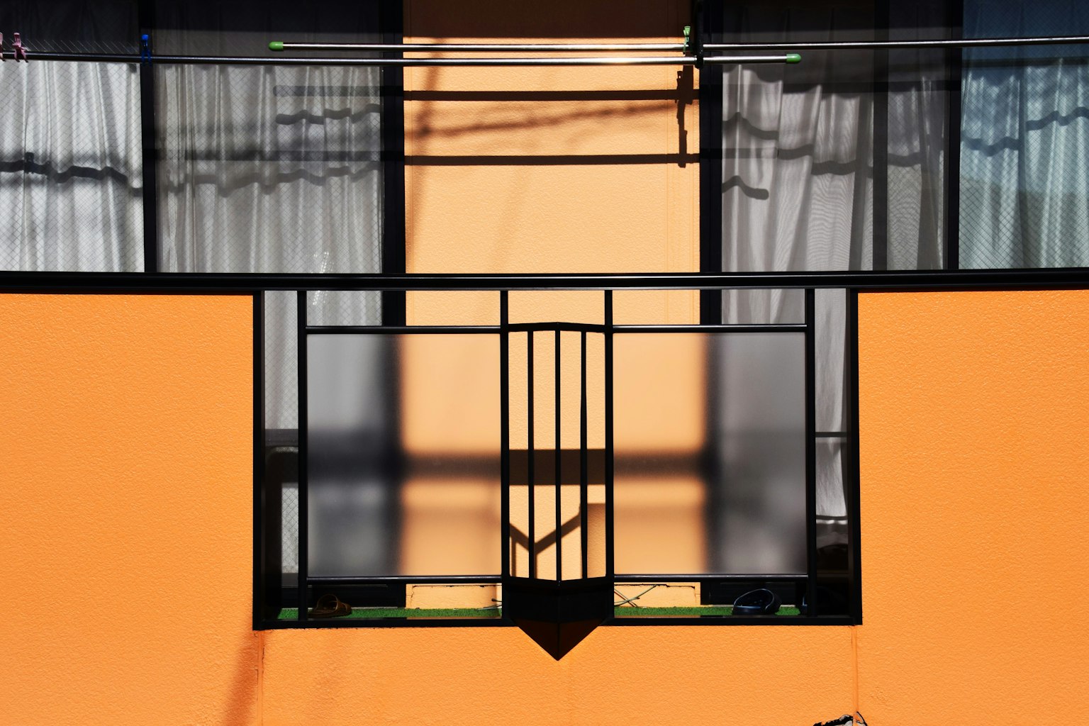 Vue extérieure d'un bâtiment avec mur orange cadres de fenêtres noirs et rideaux