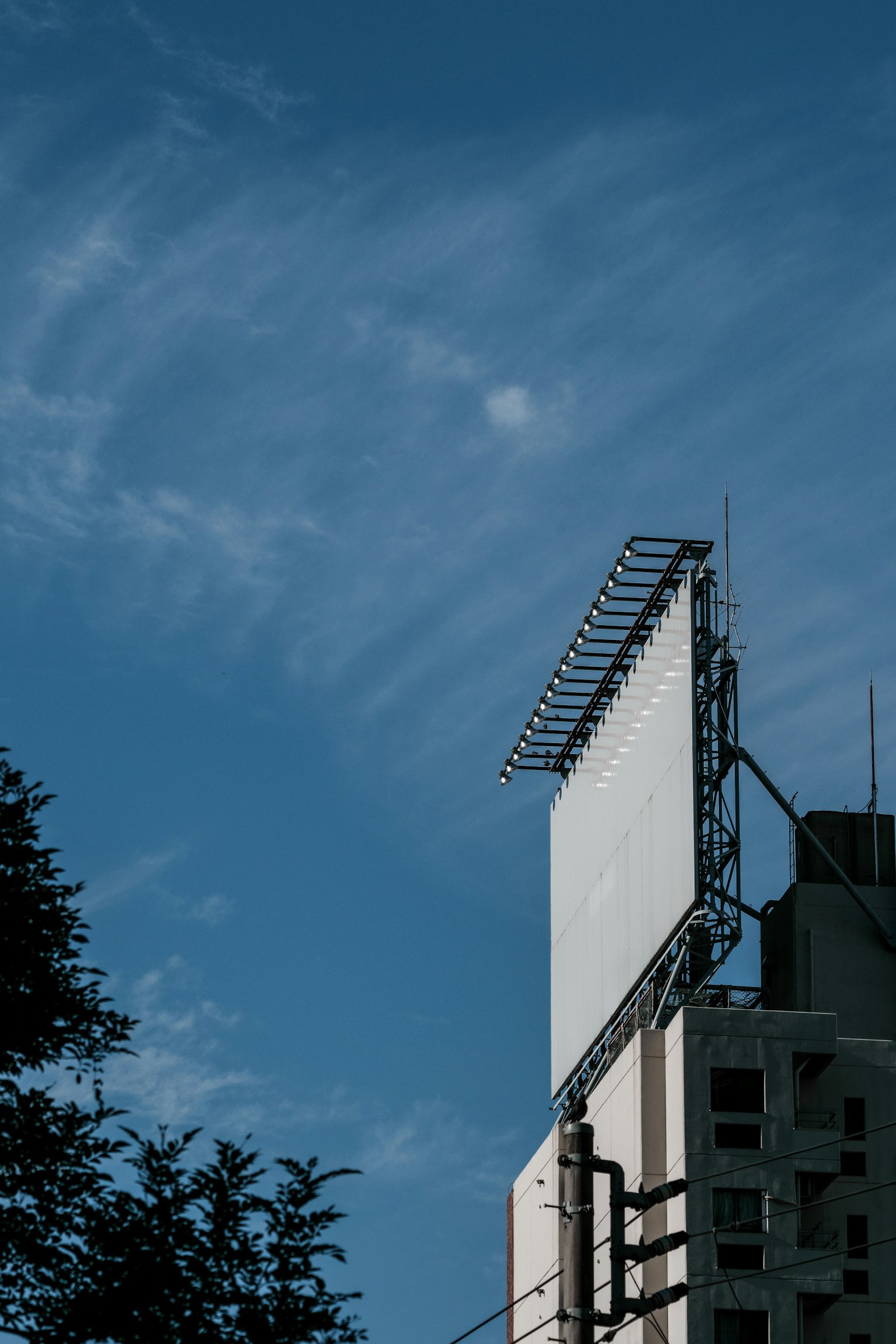 Gran cartel vacío contra un cielo azul con un edificio parcialmente visible
