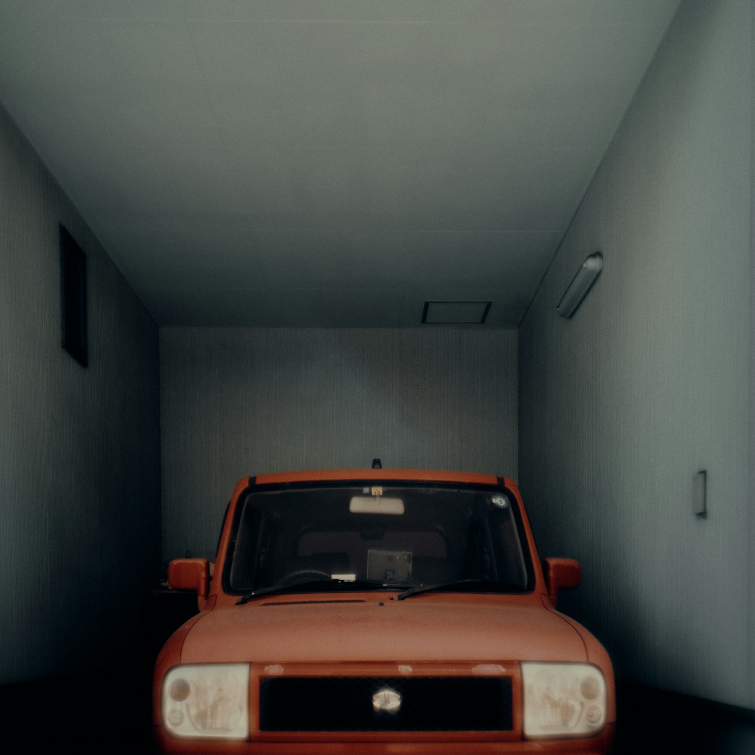 Auto rossa parcheggiata in un garage con pareti blu