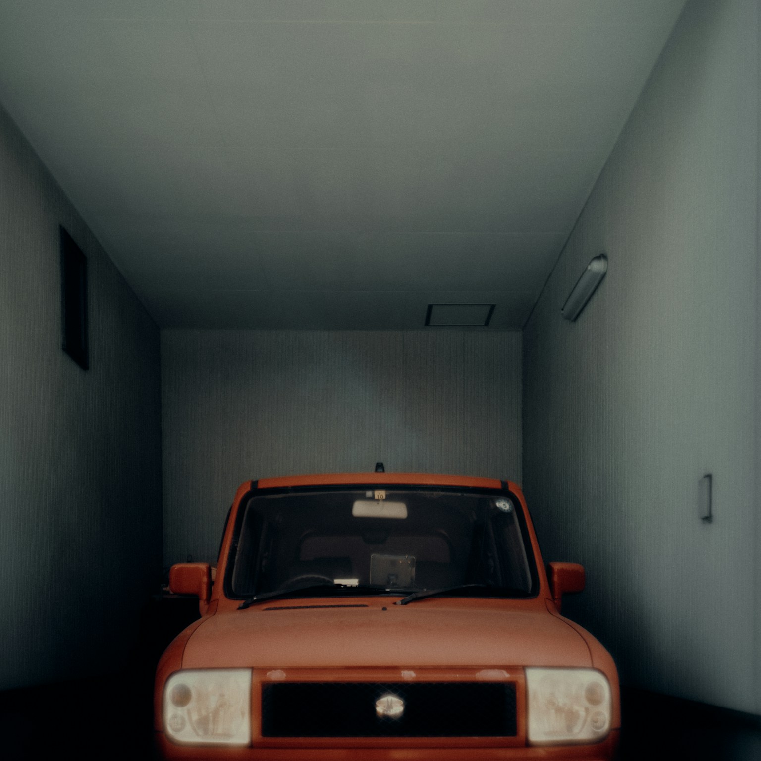 Auto rossa parcheggiata in un garage con pareti blu
