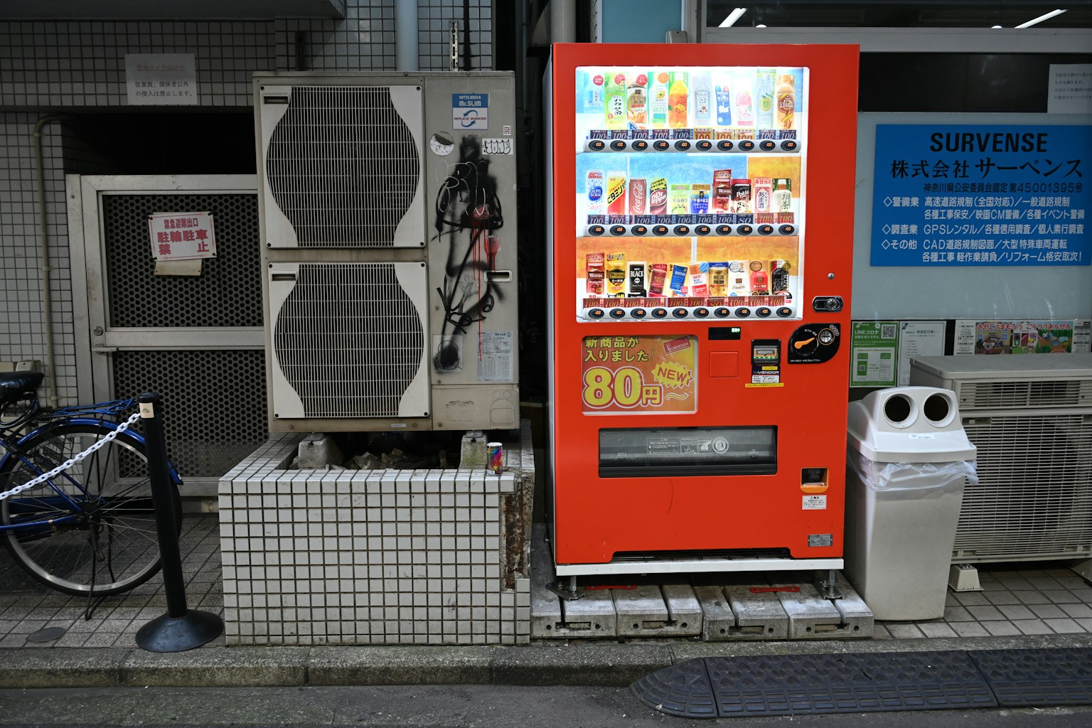街角景觀有一個紅色自動販賣機和一個垃圾桶