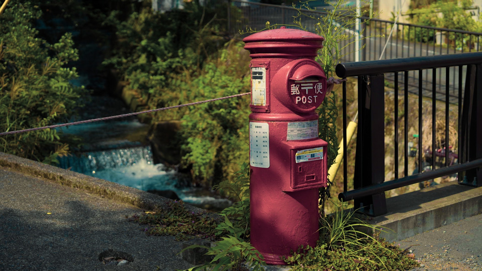 A red mail post standing near a river