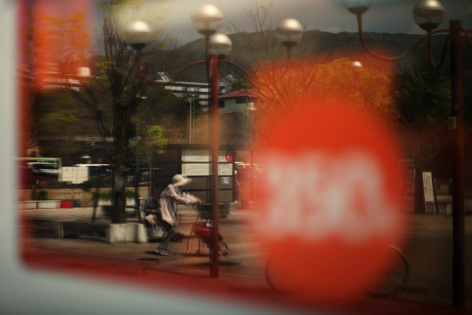 Người đang đi xe đạp nhìn qua cửa sổ với một vật thể hình tròn màu đỏ mờ ở phía trước