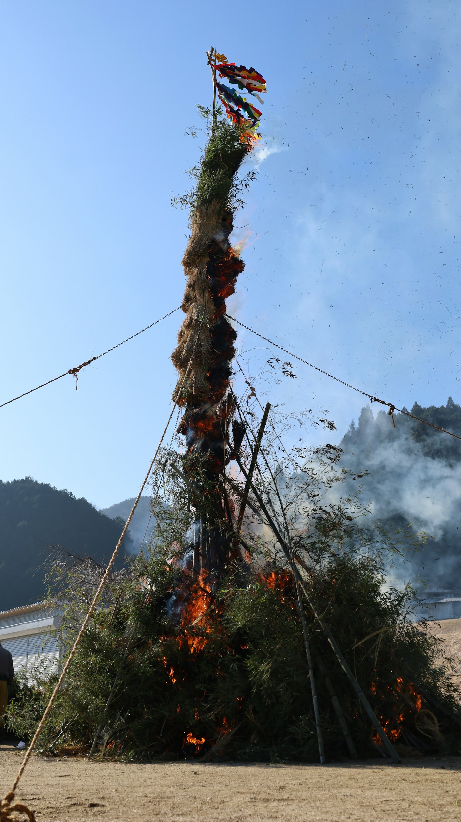 高耸的篝火与火焰和烟雾，背景为山脉