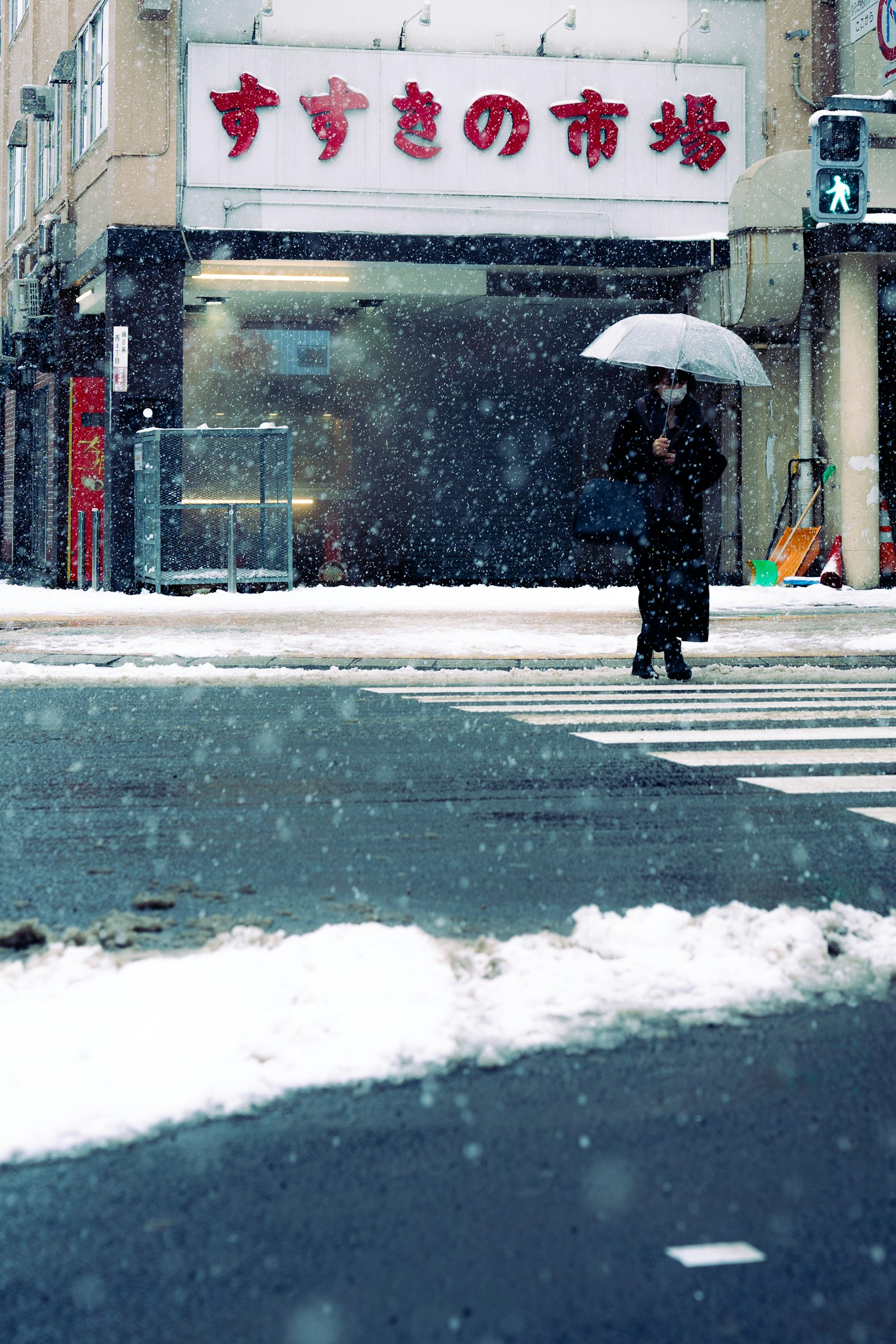 Una persona caminando con un paraguas en la nieve en un paso de peatones