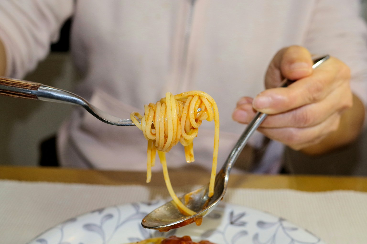 A fork lifting spaghetti with tomato sauce on a plate