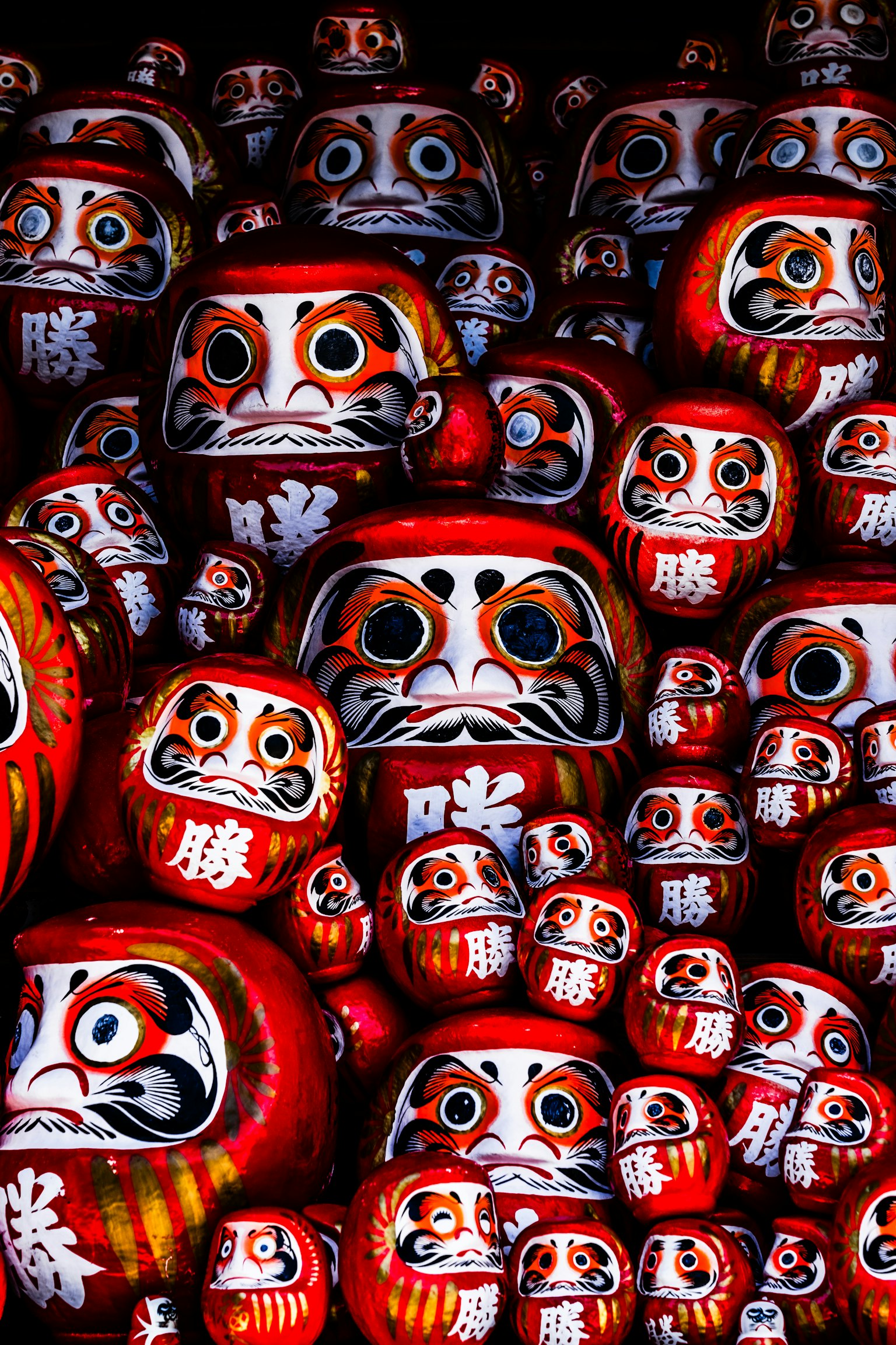 Une multitude de poupées Daruma rouges avec diverses expressions faciales