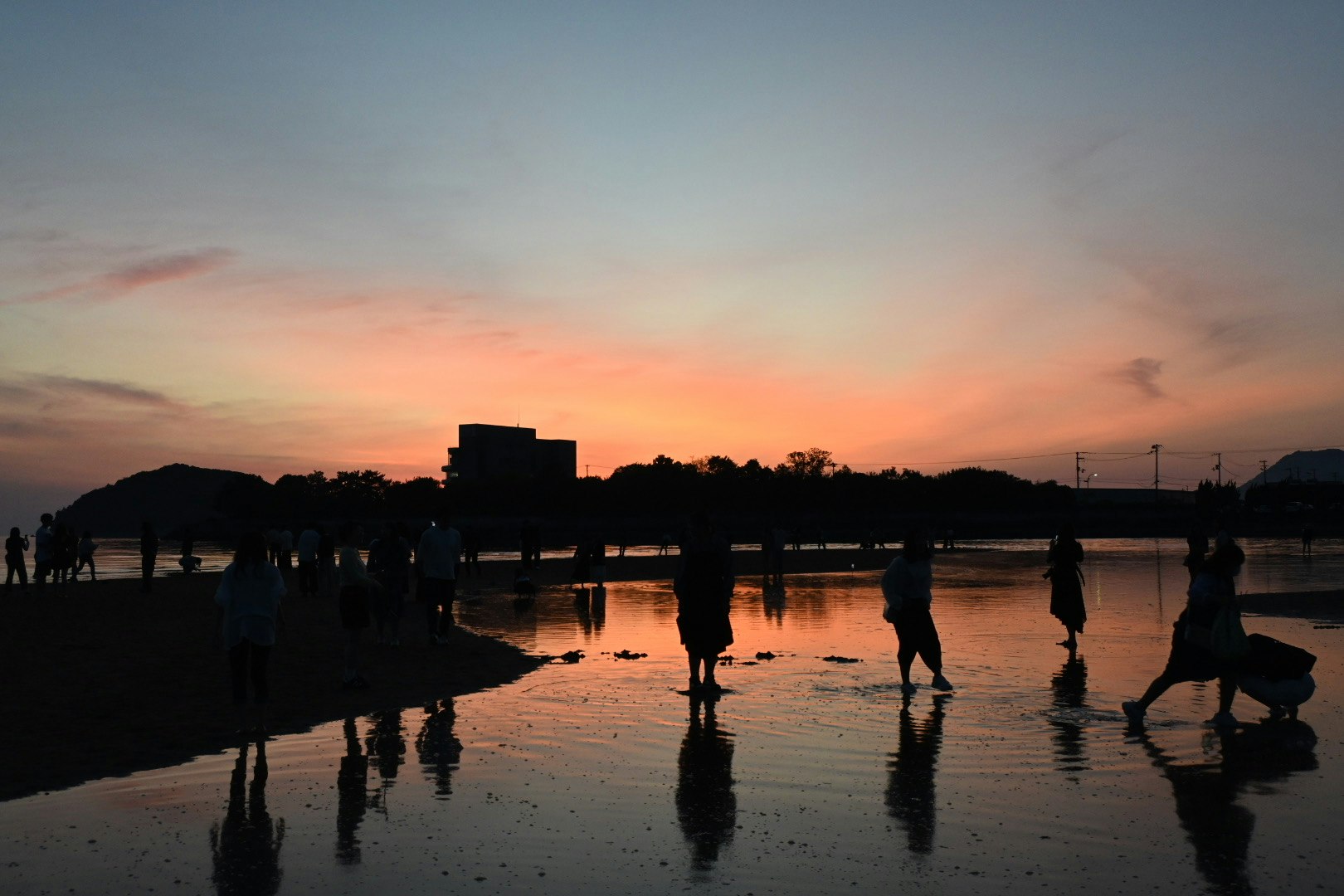 夕焼けの海辺を歩く人々のシルエット