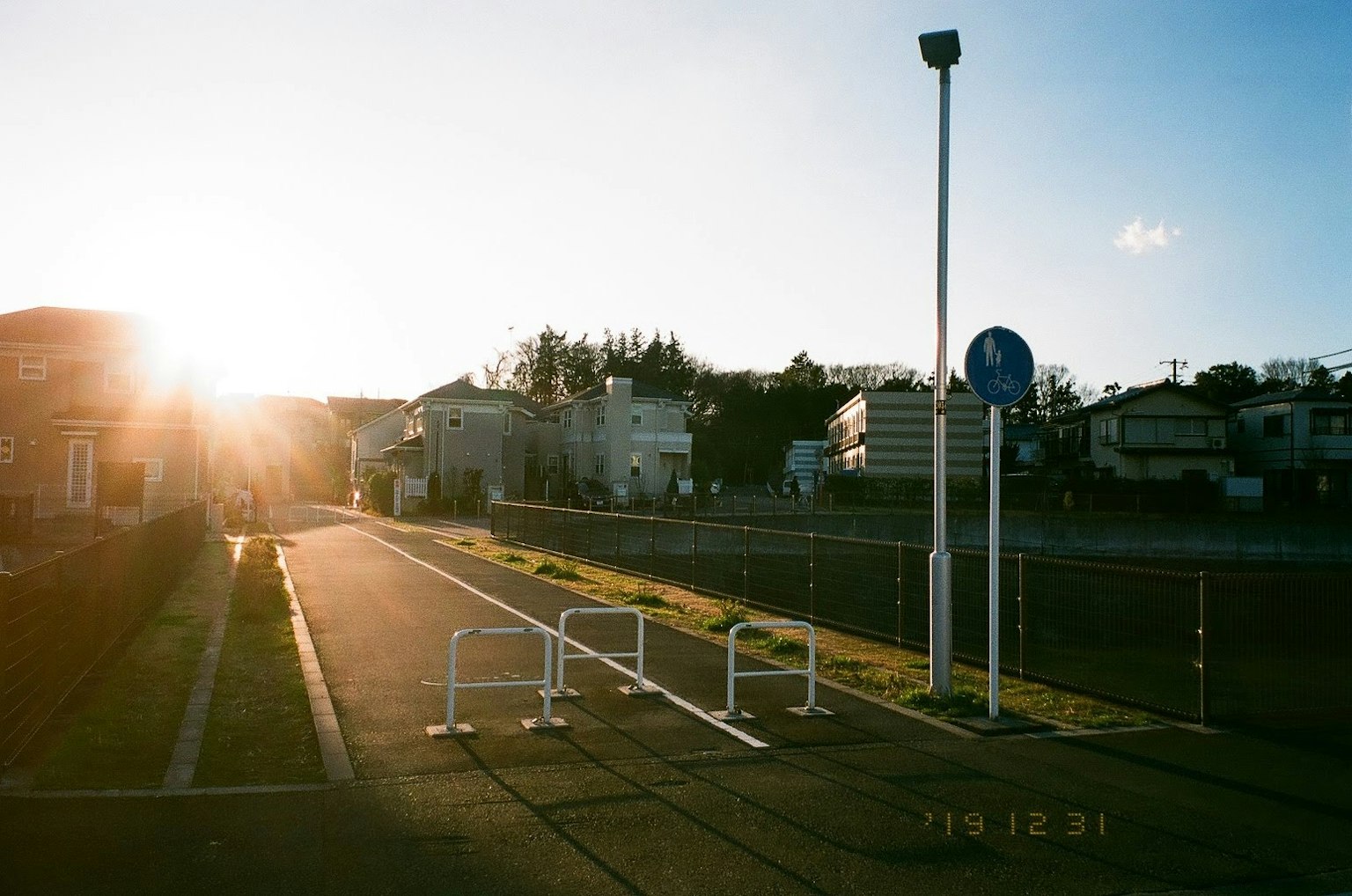 A serene street scene with sunlight and white barriers