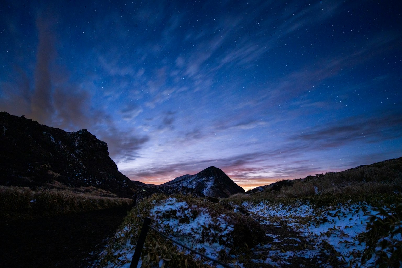 Snow-covered mountains under a blue sky at dusk