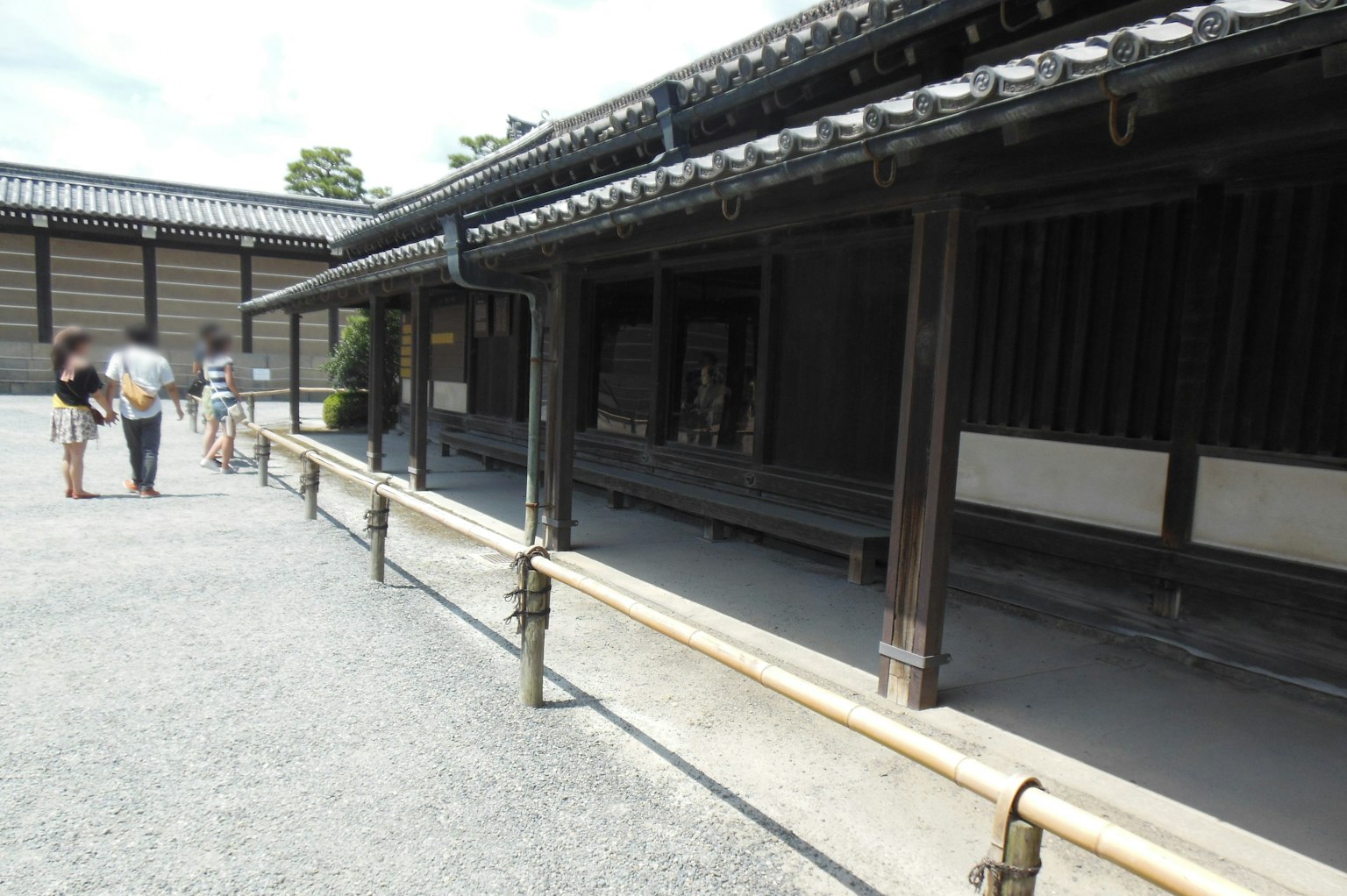 Visitors walking along a stone path beside a traditional Japanese building