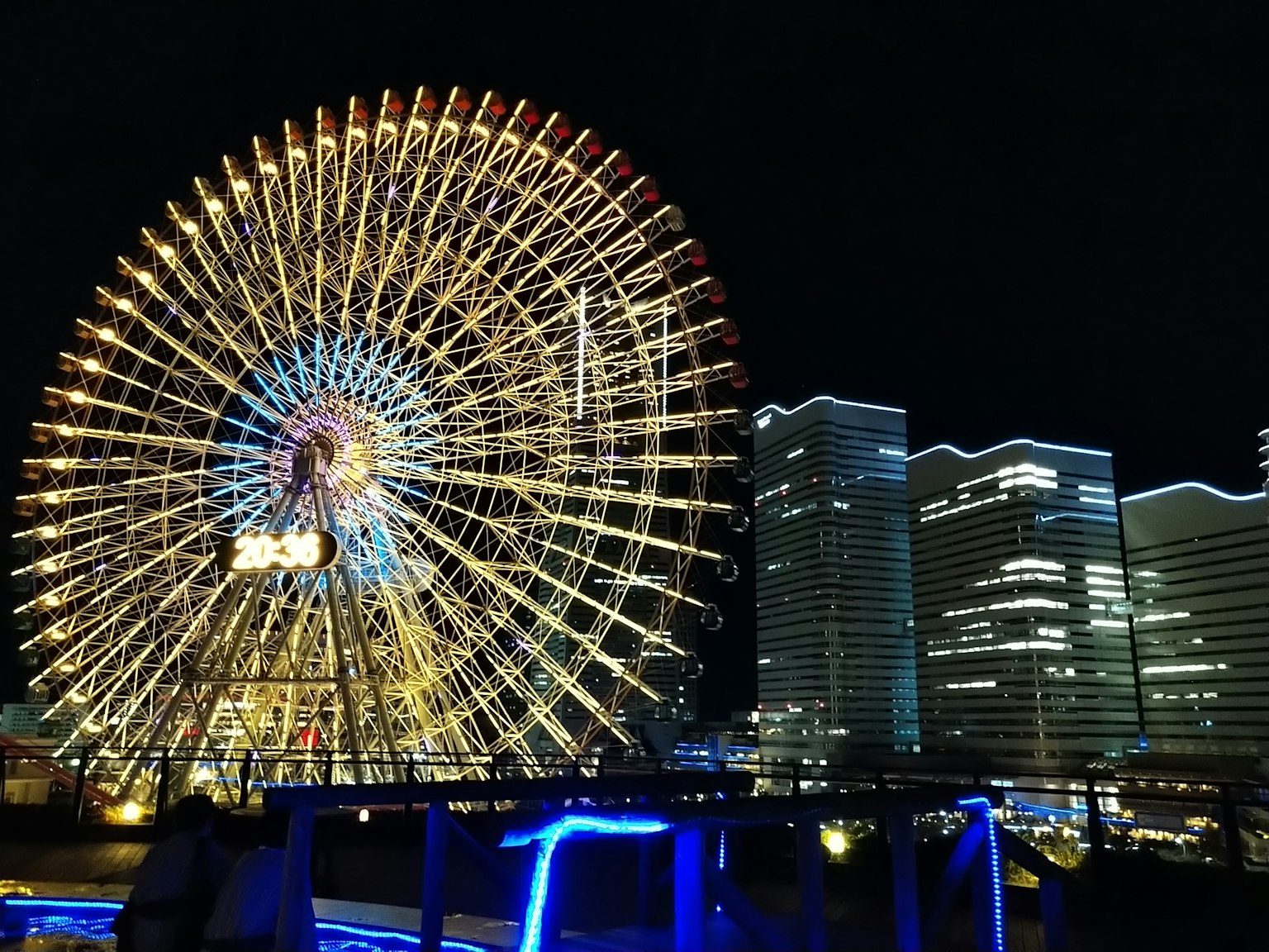 Une grande roue colorée et des gratte-ciel modernes illuminés la nuit