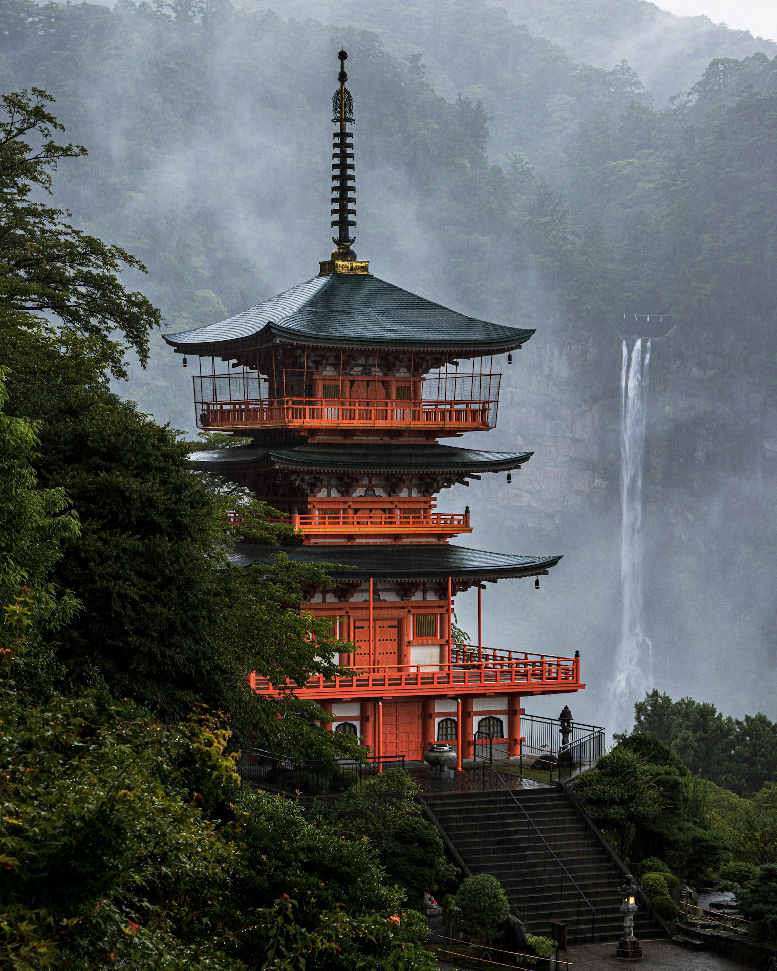 Fünfstöckige Pagode in der Nähe eines schönen Wasserfalls umgeben von üppigem Grün