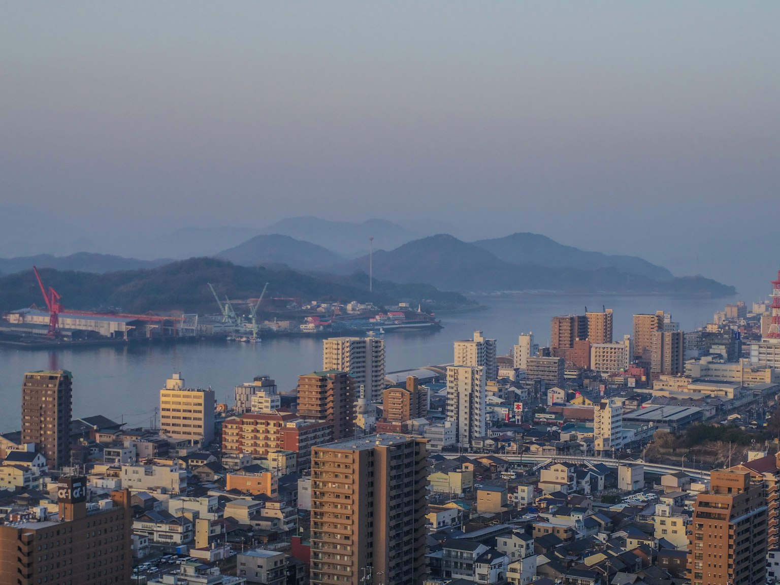 Panoramablick auf eine Stadt mit Ozean und Bergen im Hintergrund