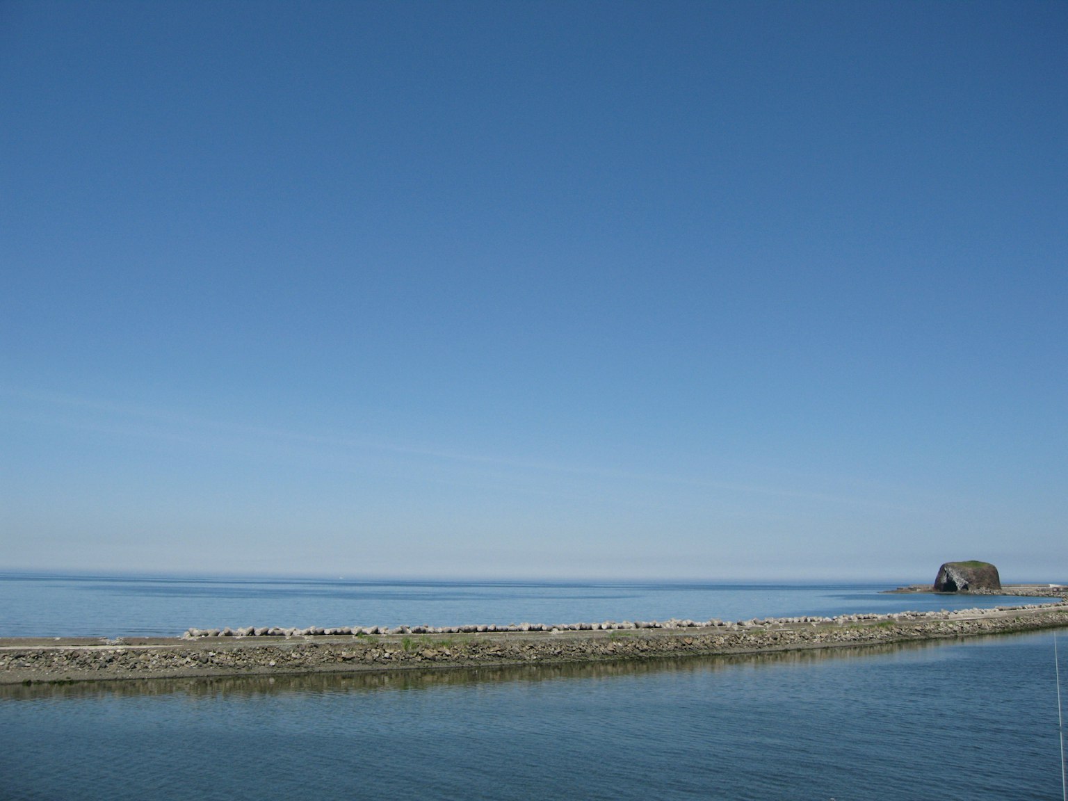 Un paesaggio sereno con cielo azzurro e mare calmo con una piccola capanna