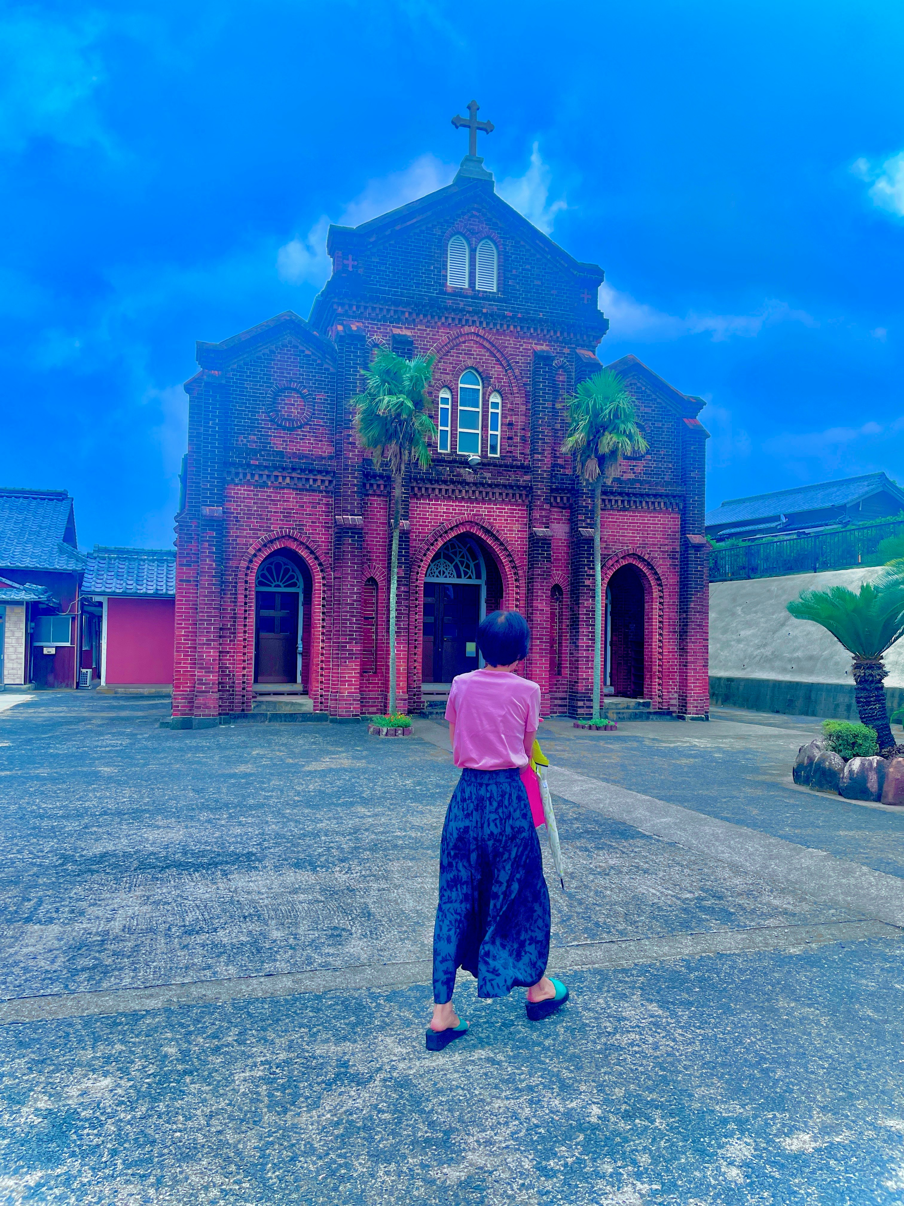 A person looking up at a church building under a blue sky