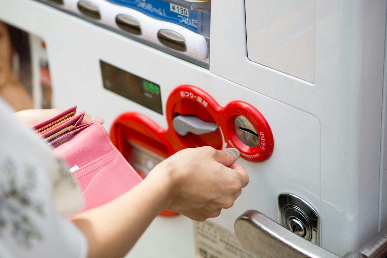 Hand inserting coin into red coin slot
