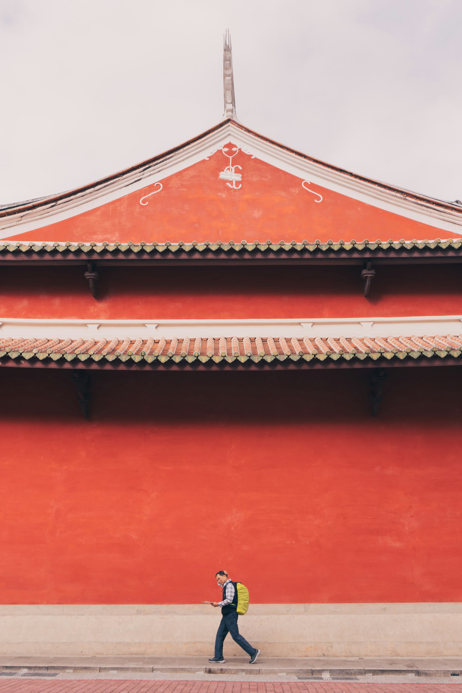 Người đi bộ trước bức tường đỏ với mái truyền thống