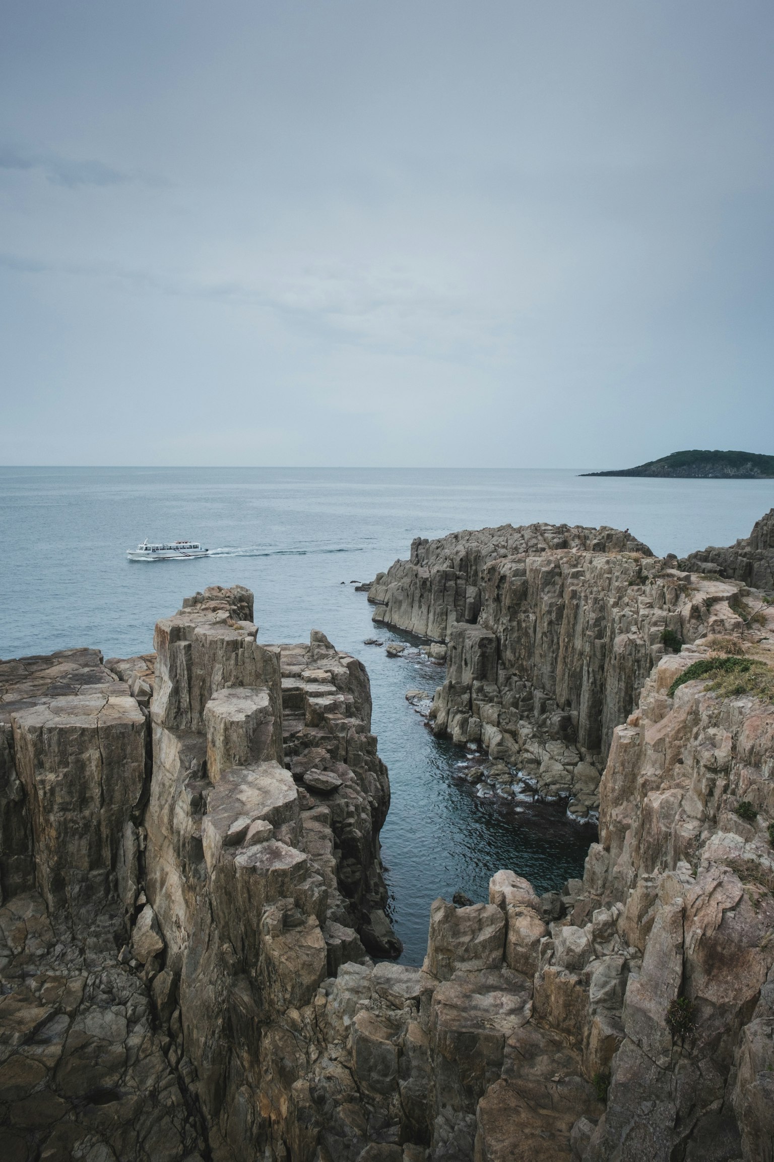 Paysage maritime avec des falaises rocheuses et des eaux calmes sous un ciel nuageux