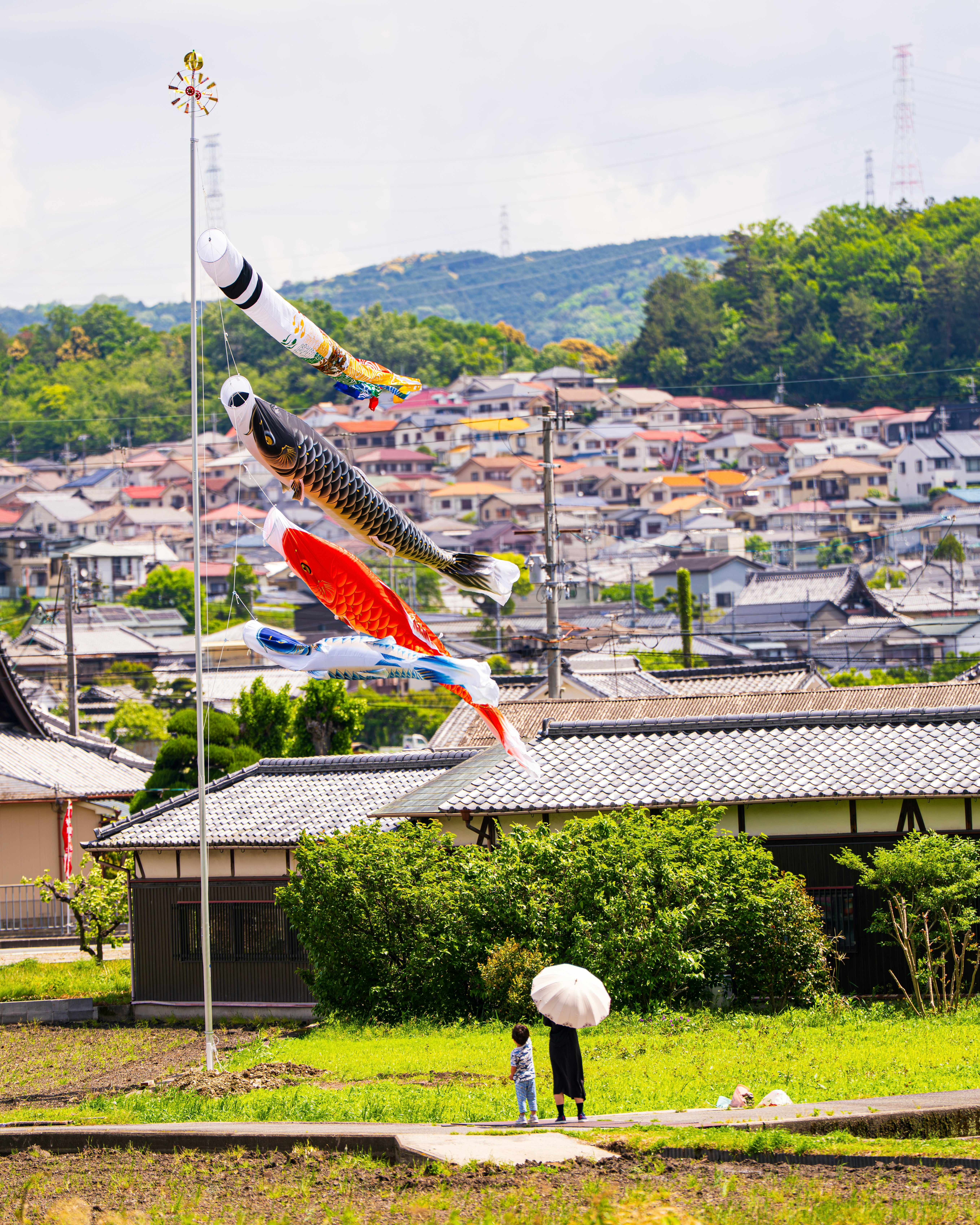 鯉のぼりを見上げる親子と町並みの風景