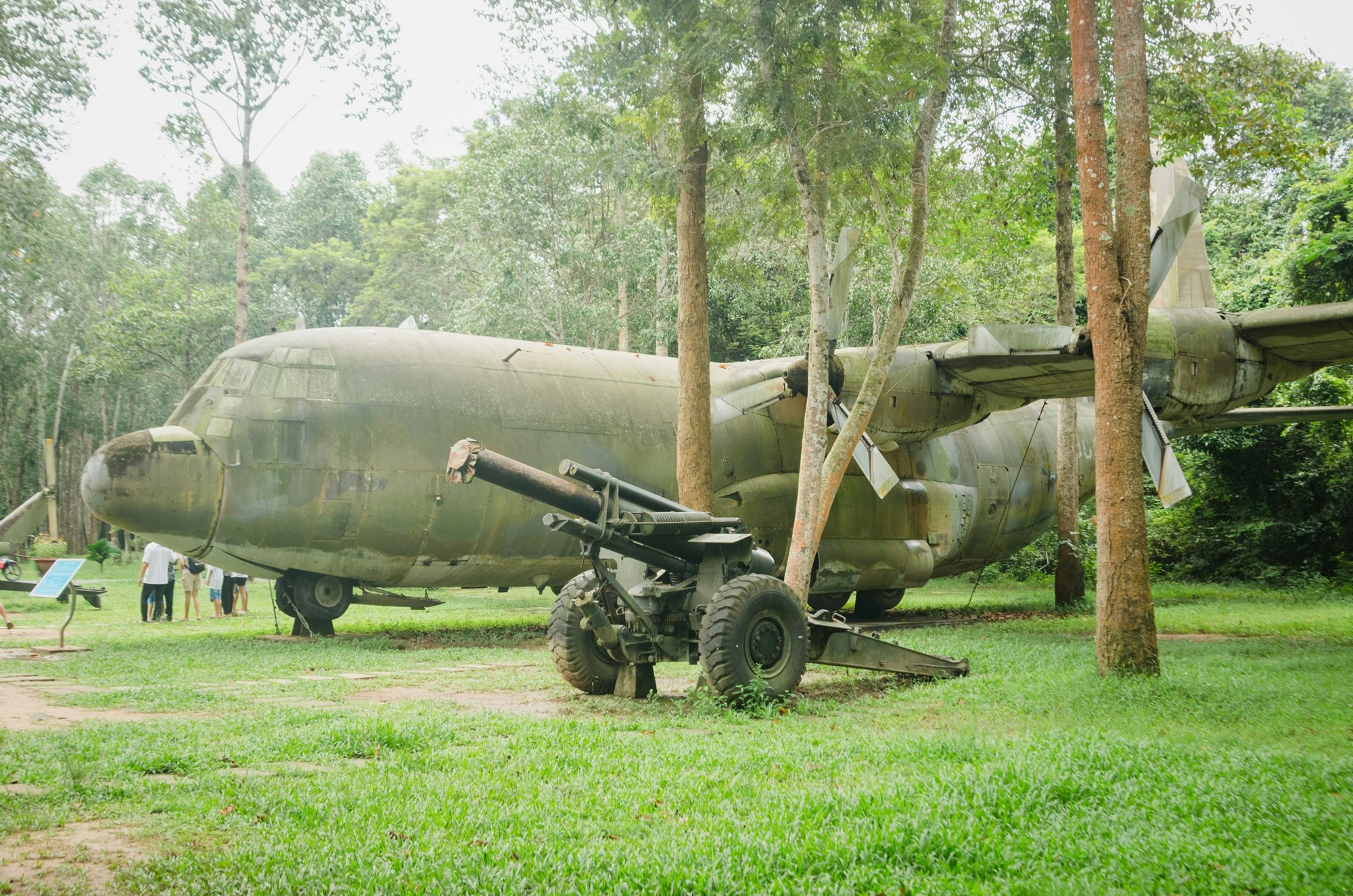 熱帯の草地に展示された軍用機の胴体と車輪