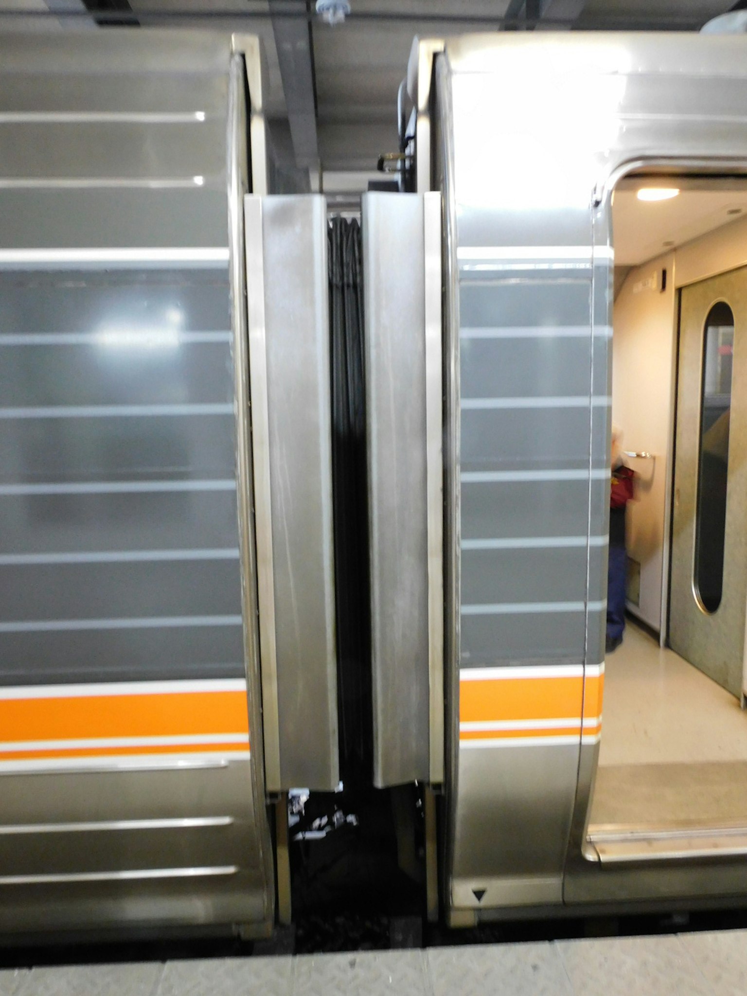Porte aperte di un treno che mostra il design interno e una striscia arancione