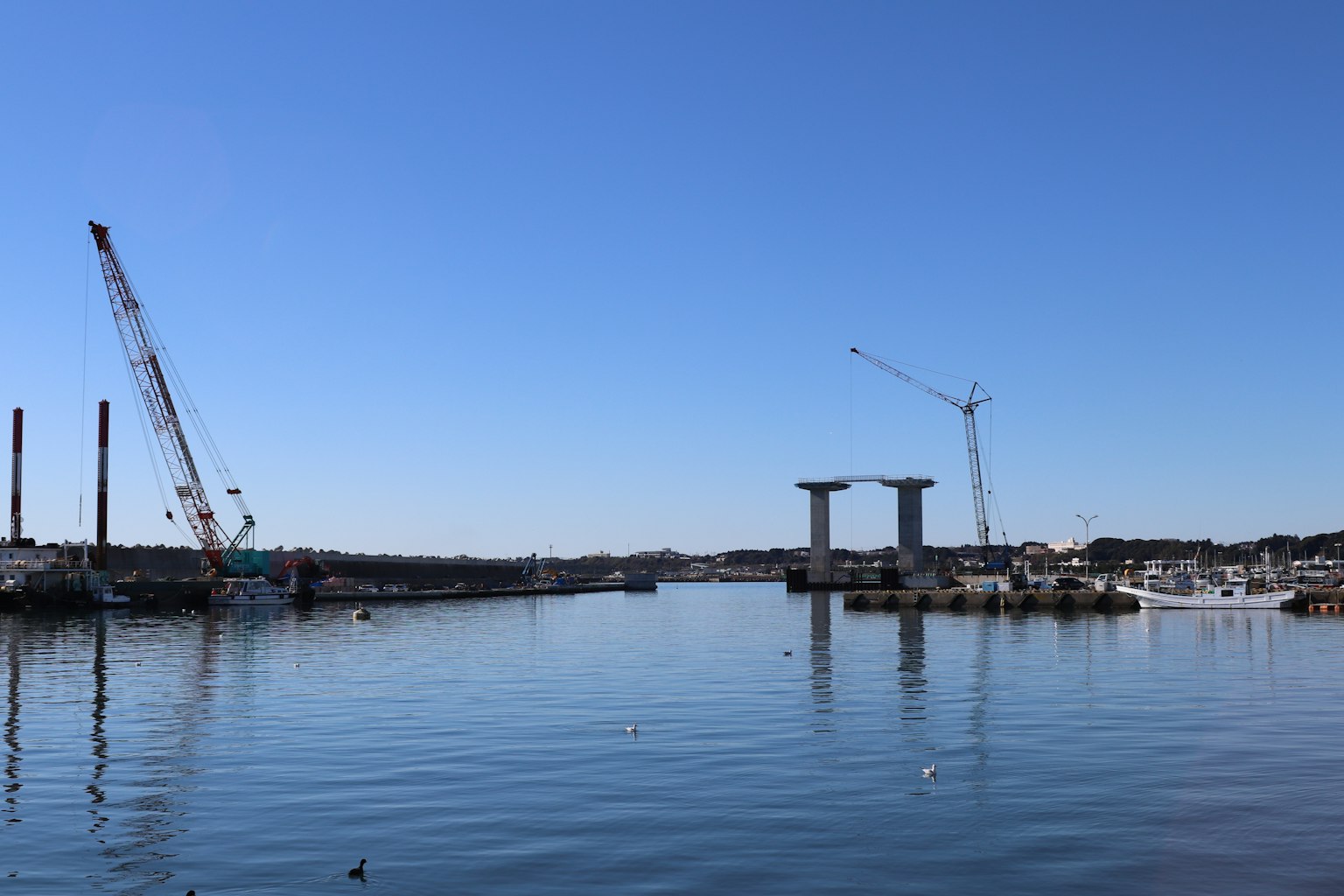 Escena del puerto bajo un cielo azul con grúas y estructuras en construcción