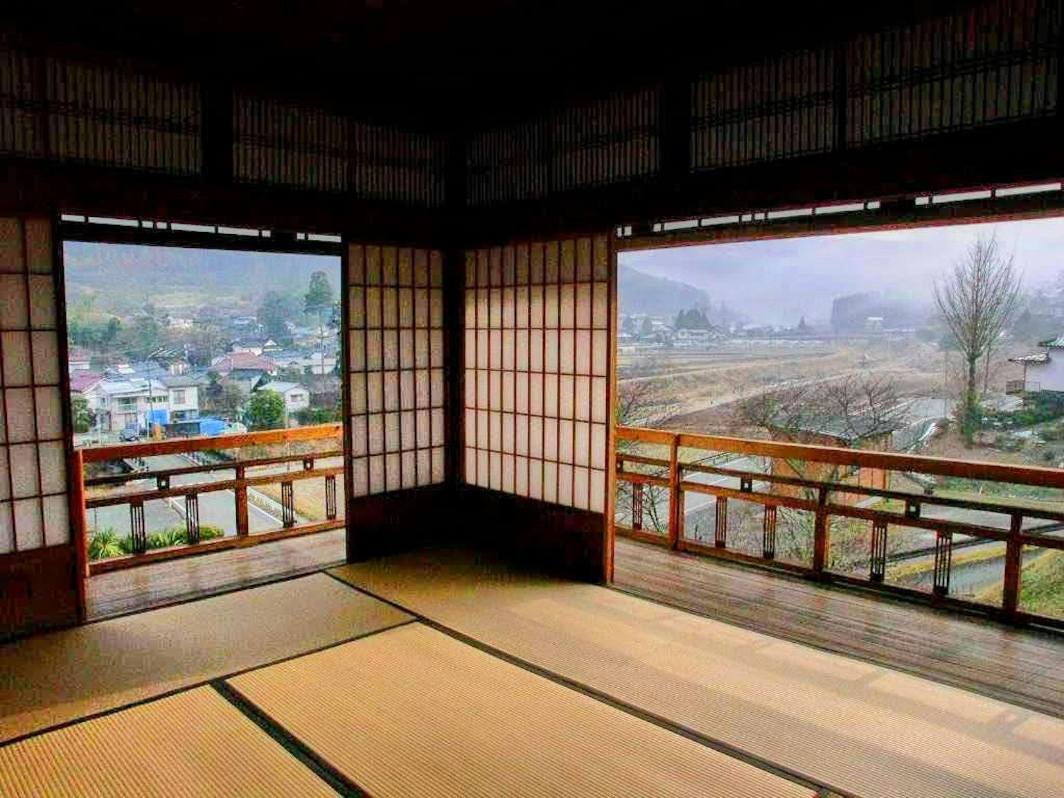 Blick aus einem traditionellen japanischen Raum mit Shoji-Fenstern auf Berge und ein Dorf