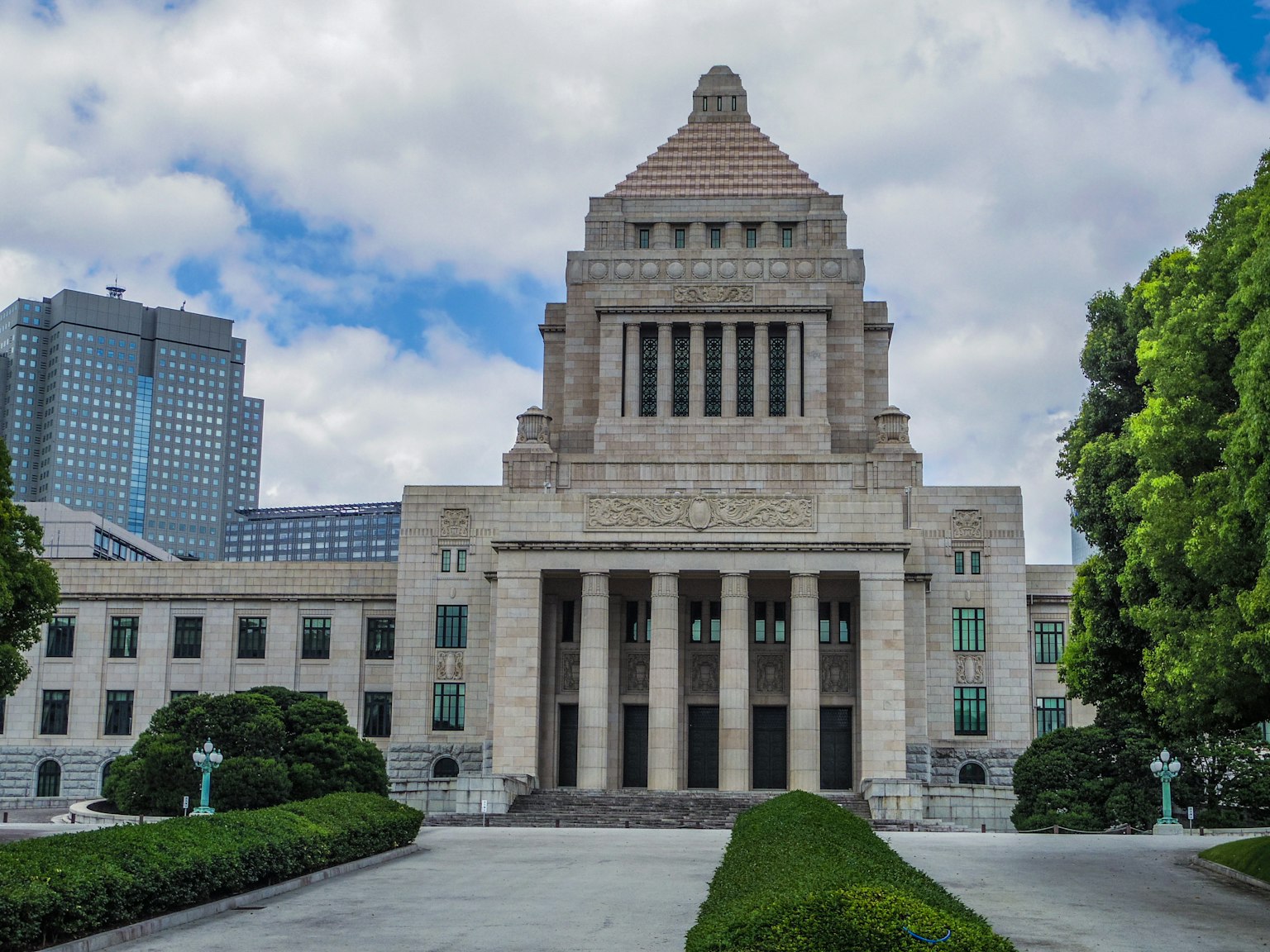Vista exterior del edificio del Dieta Nacional de Japón con rascacielos modernos y vegetación
