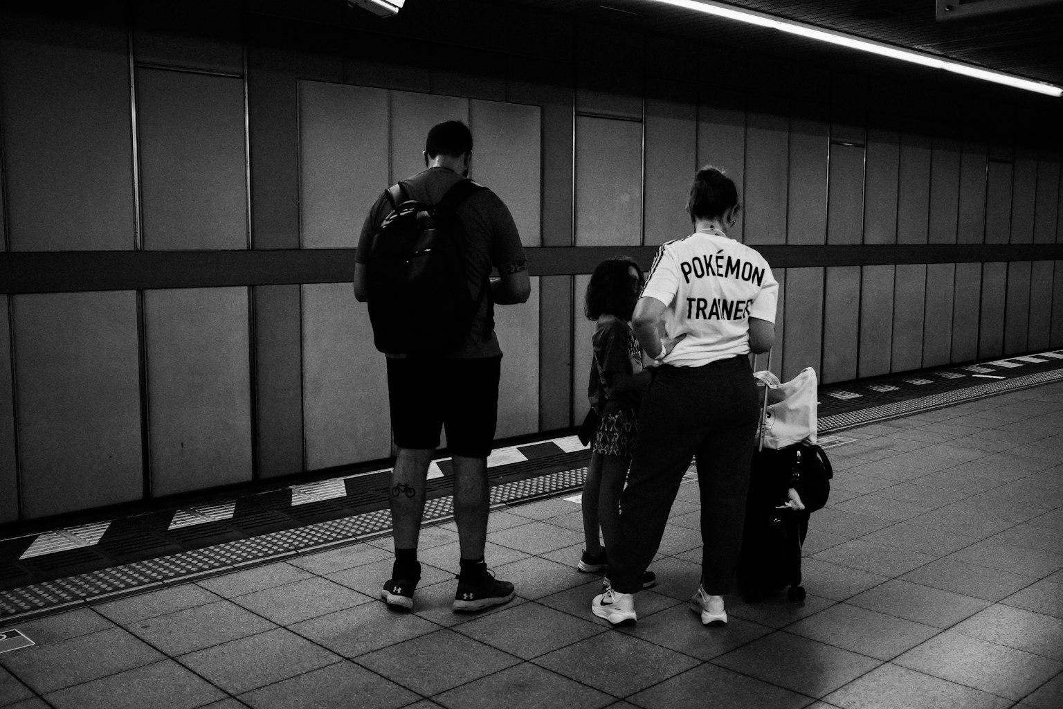 Two men and a child waiting on a subway platform