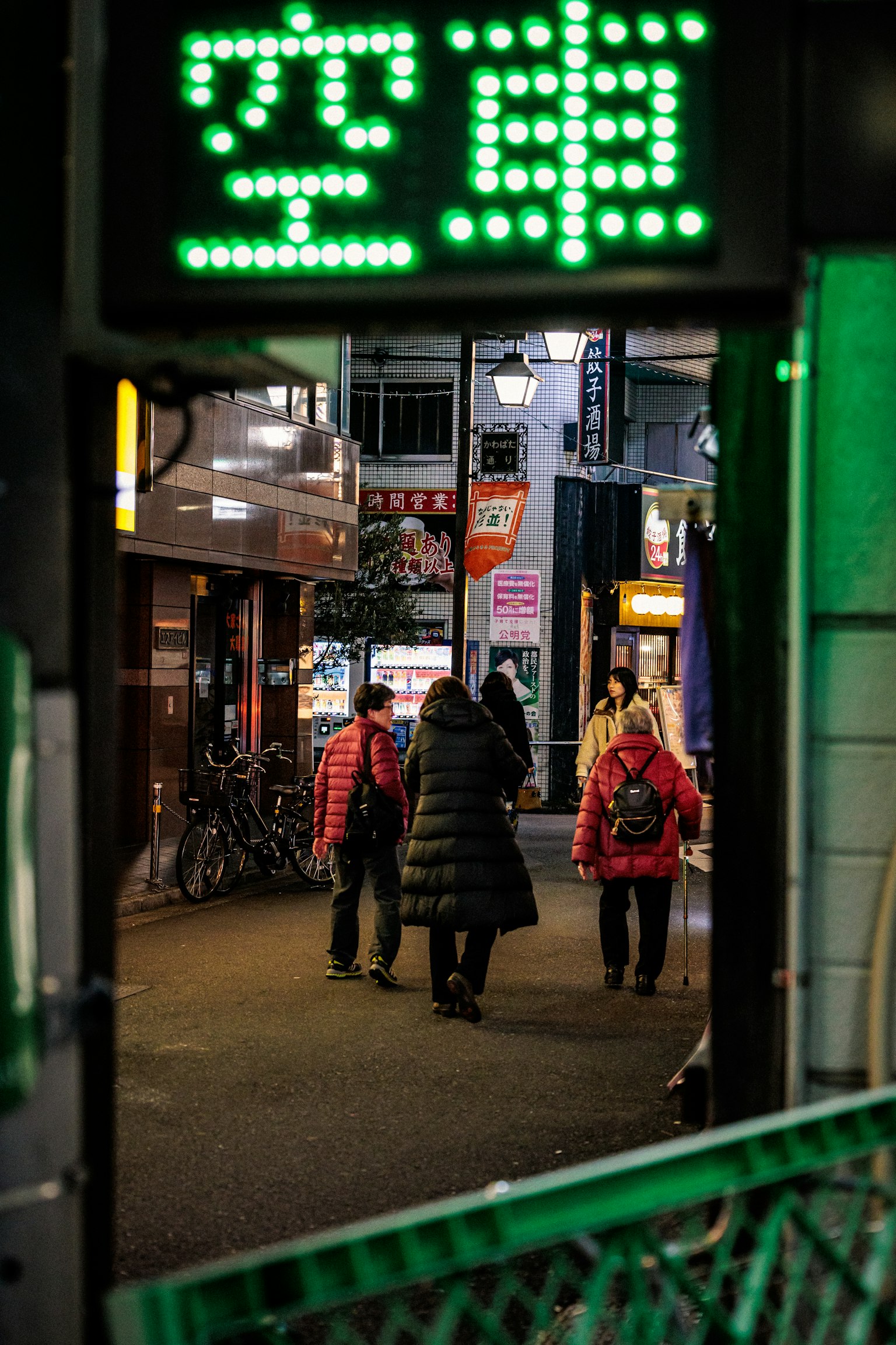 夜間街道場景,人們走在綠色霓虹燈招牌下
