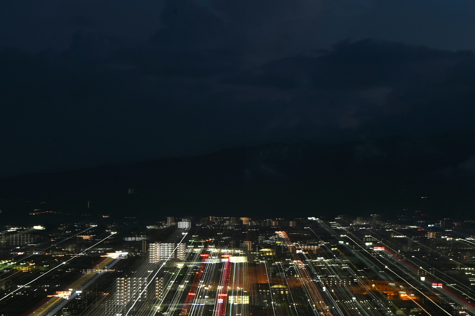 ทิวทัศน์เมืองในเวลากลางคืนพร้อมไฟส่องสว่างและการจราจรที่เคลื่อนไหว