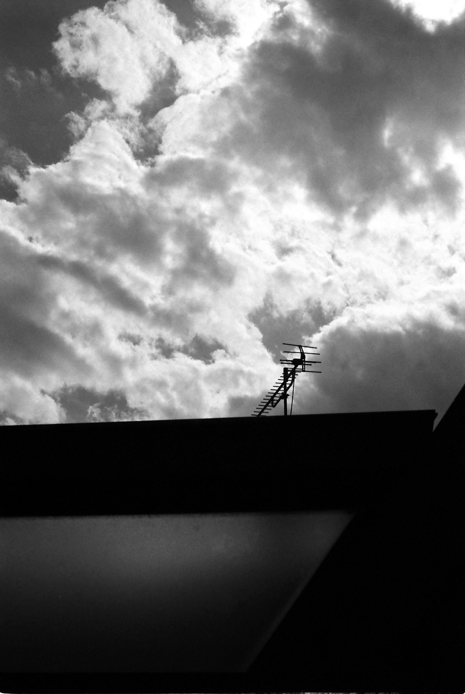 Silhouette di un tetto contro nuvole drammatiche in bianco e nero