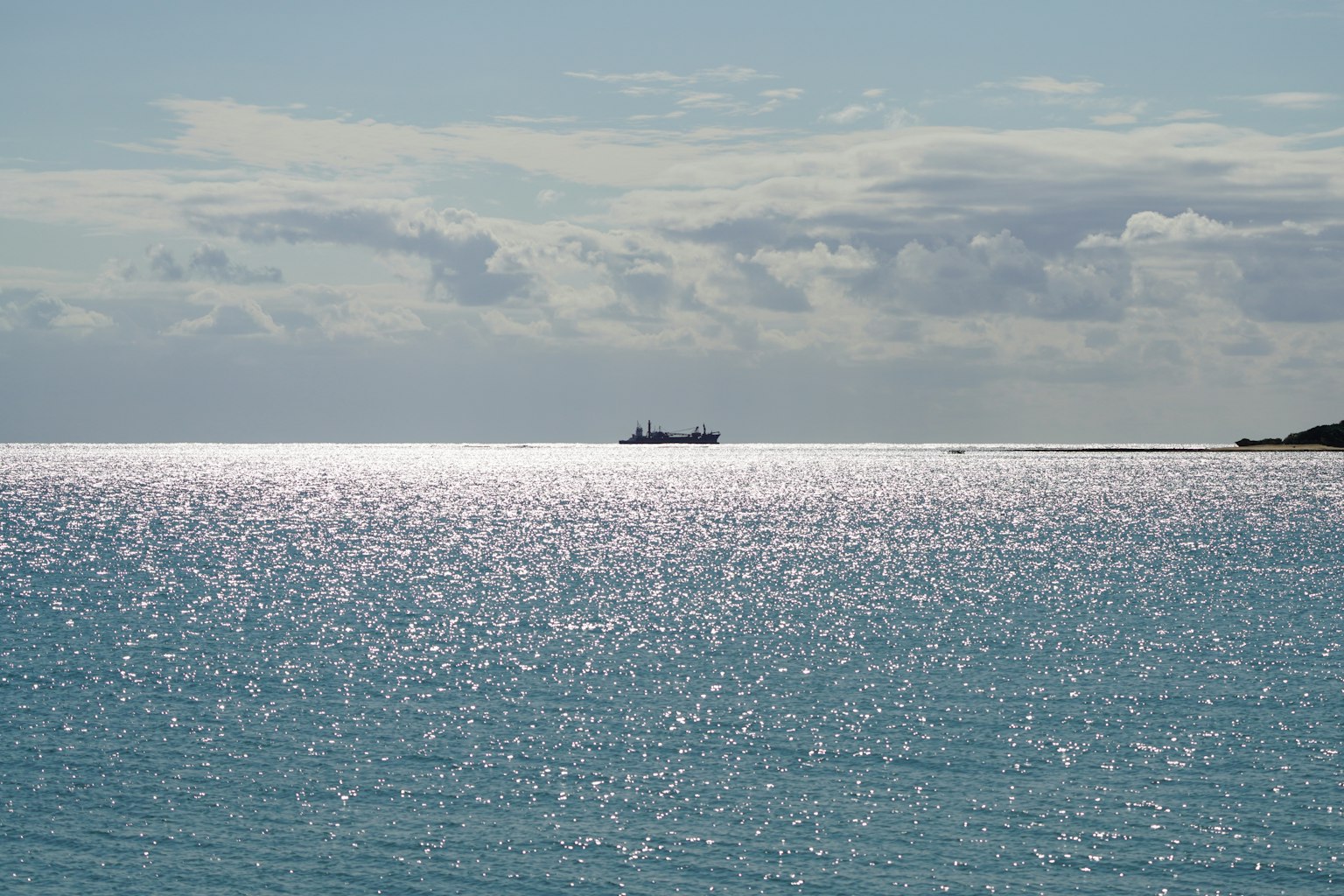 Un paesaggio marino sereno con acqua scintillante e una nave in lontananza