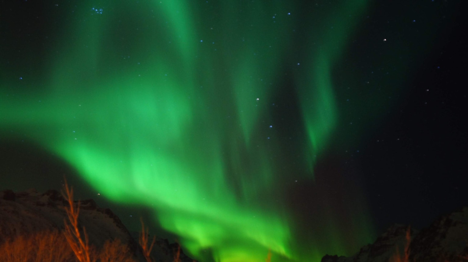 Lebendige grüne Aurora-Lichter tanzen am Nachthimmel