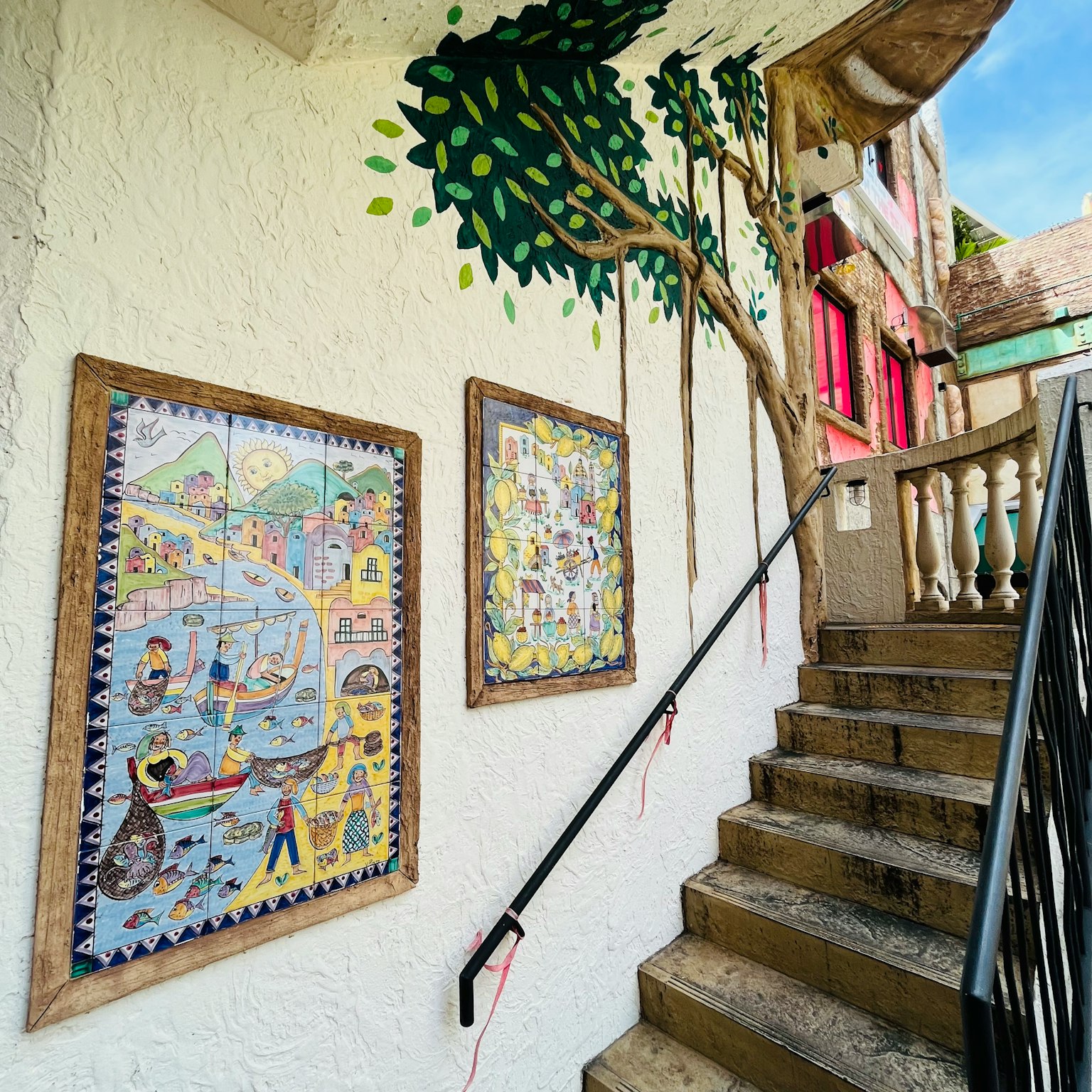 Arte in piastrelle colorate e design di albero murale lungo la scala