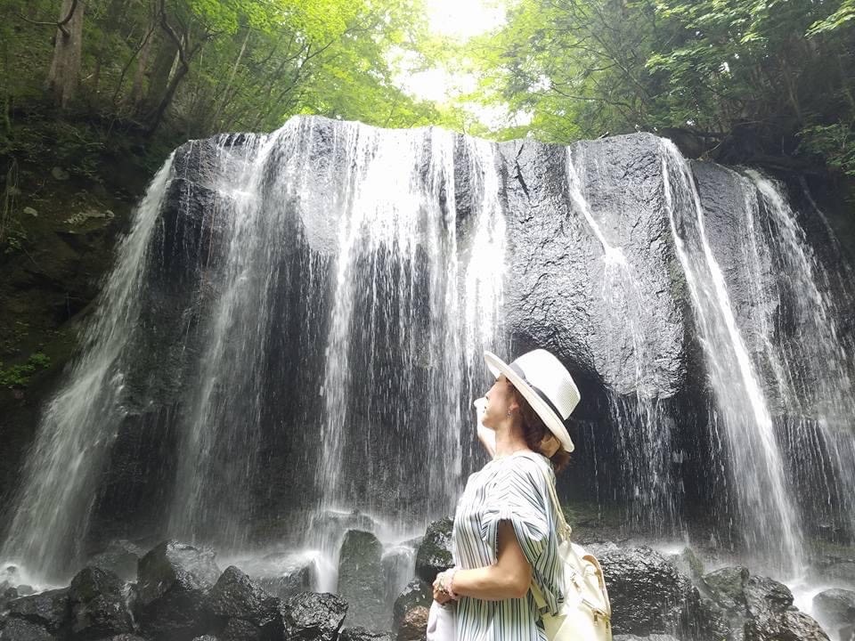滝の前で見上げる白い帽子の旅行者