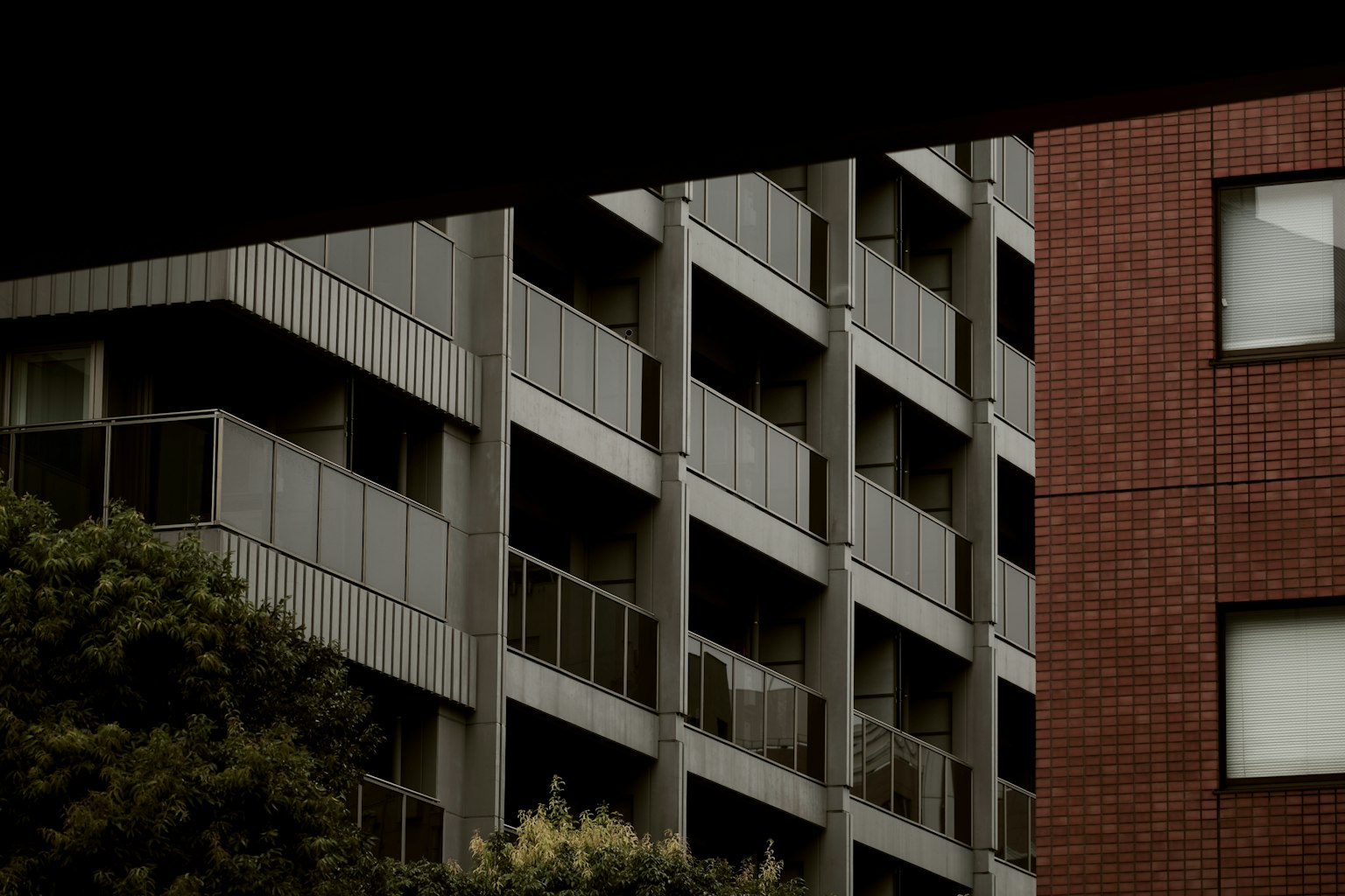 Immeuble moderne avec des tons sombres et des balcons verdoyants au premier plan