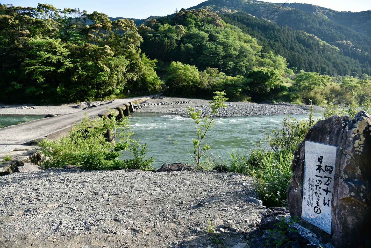 Vue pittoresque d'une rivière entourée de verdure et d'un pont avec une pierre gravée