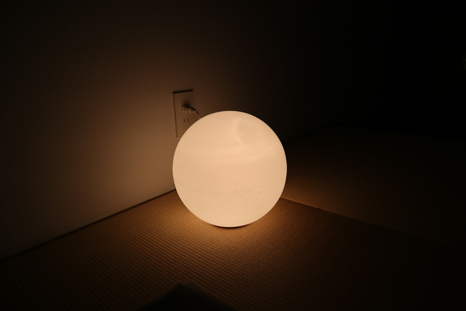 Une lampe ronde émettant de la lumière placée contre un mur