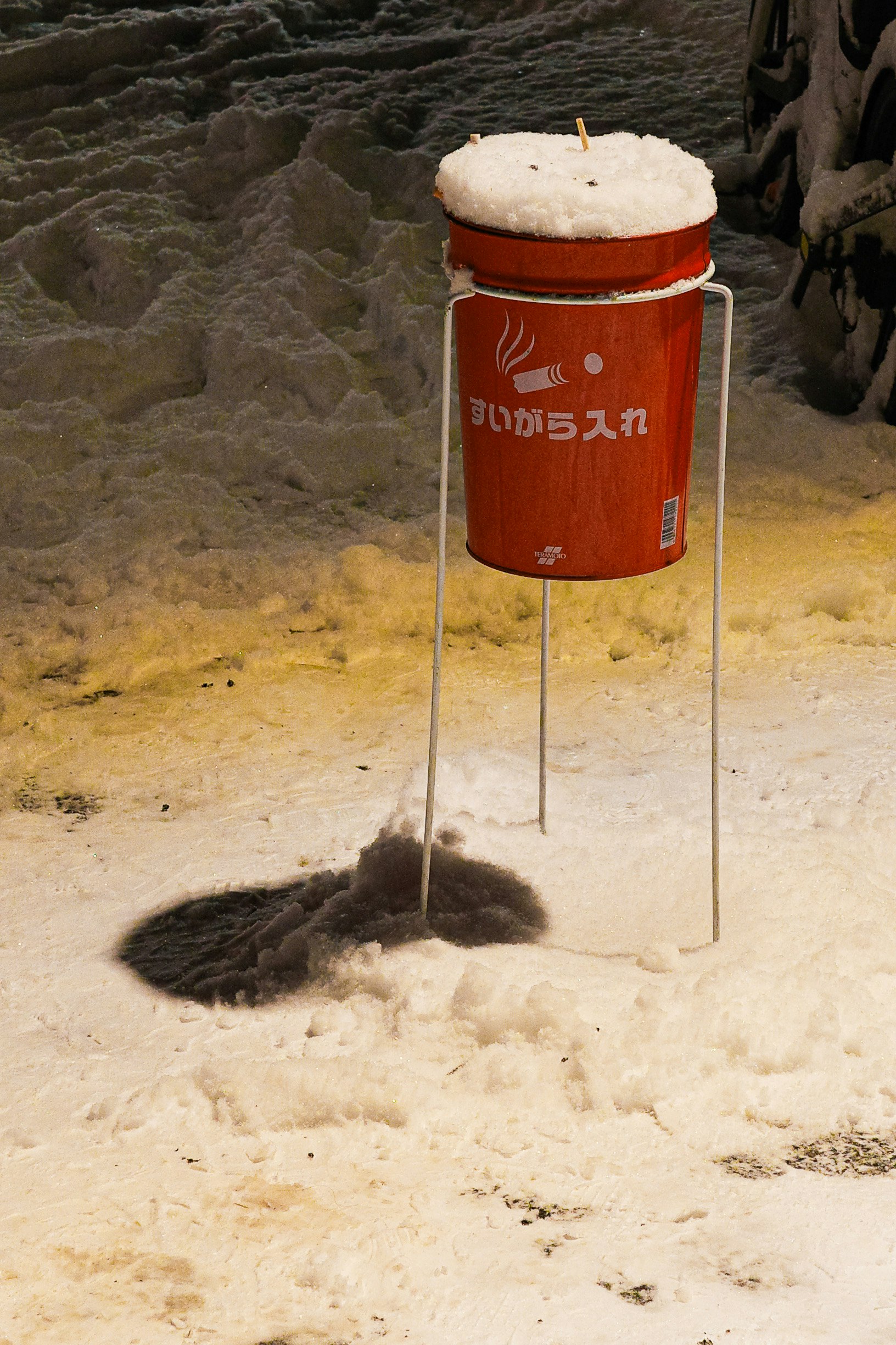 雪の上に置かれた赤いバケツとその影