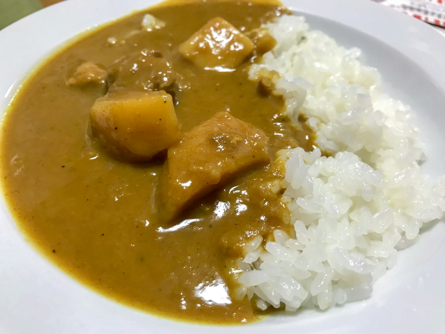 Plato de curry con arroz que presenta grandes trozos de verduras en una salsa espesa
