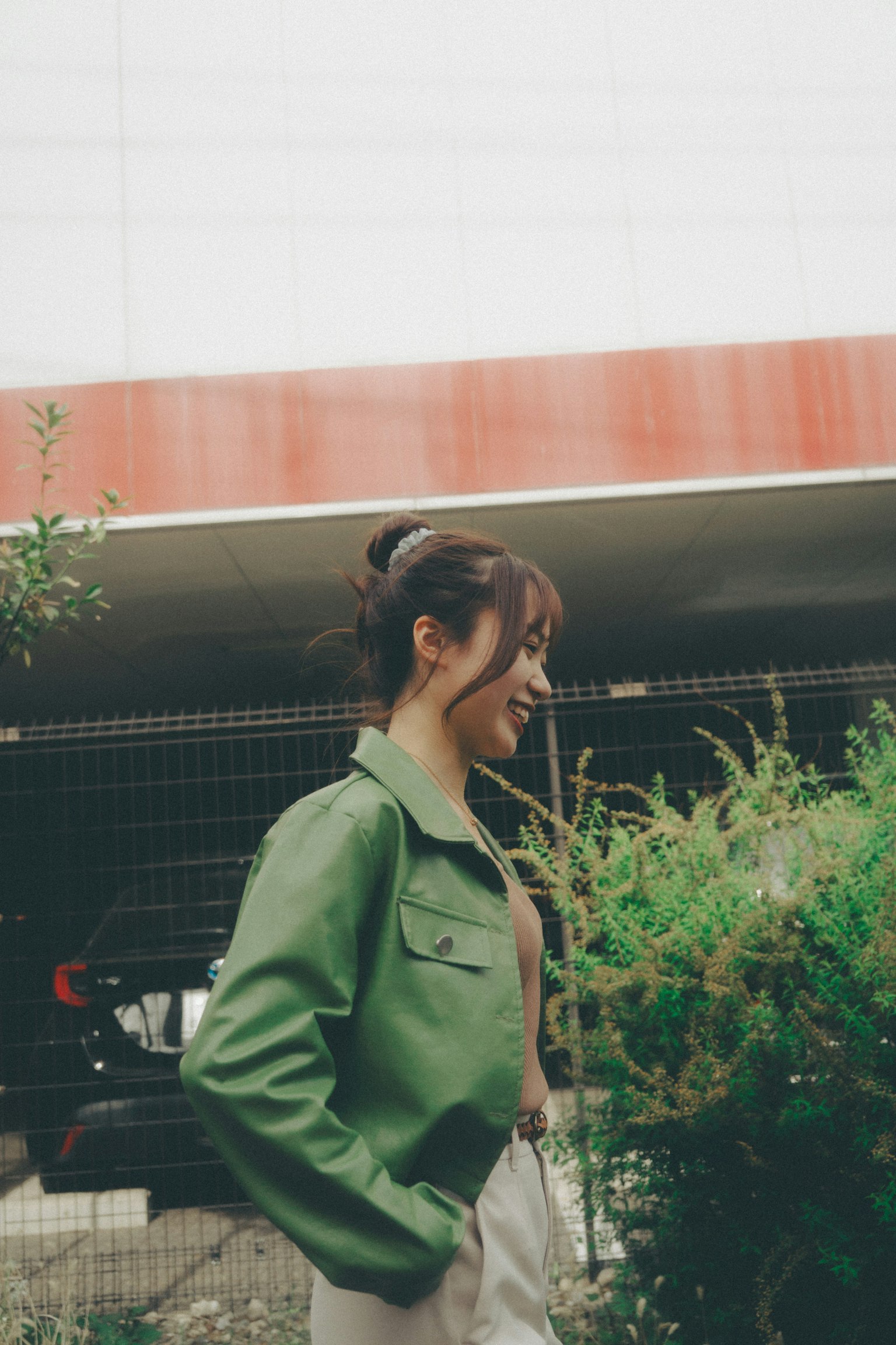 穿著綠色夾克的女性在植物旁邊走