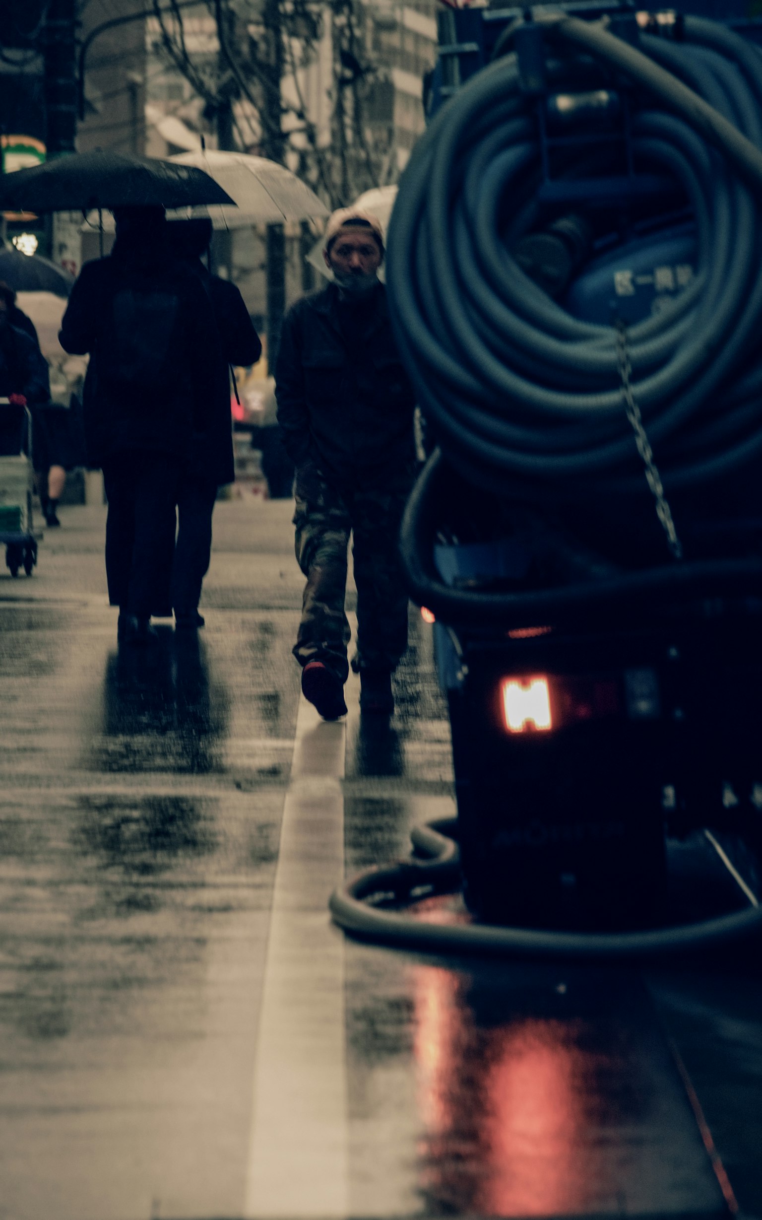 Scène de ville avec des personnes marchant sous la pluie et un tuyau au sol